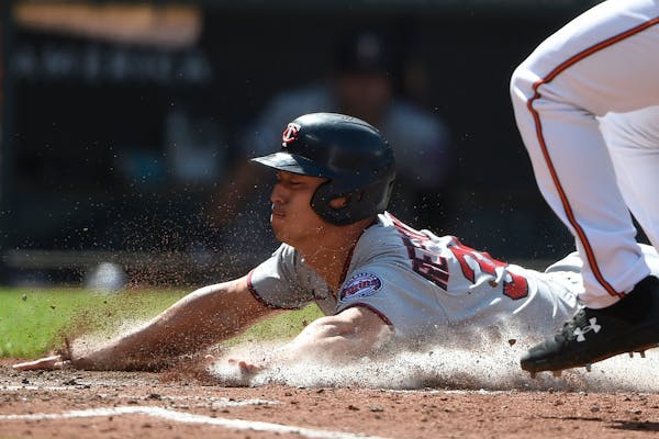 Minnesota Twins Rob Refsnyder slides across the plate with the go-ahead run Monday after crashing into the wall earlier in the game.