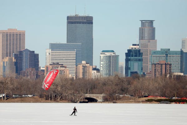Kite boarders skim across Bde Maka Ska in front of the Minneapolis skyline in March. The state's famous winters are warming 13 times faster than its s