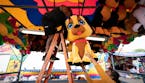 Lorraine Robitaille, right, handed Margarita Nunez a large stuffed dog as they hung prizes at their game stand in the Midway the day before opening da