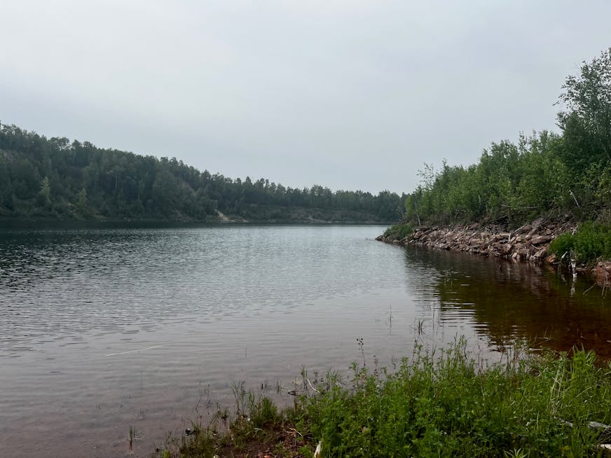 A picture of a mine pit filled with water on an overcast day.