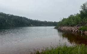 A picture of a mine pit filled with water on an overcast day.