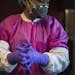 Miao Xu dresses into protective gear before working with the Zika virus in the lab at the National Center for Advancing Translational Sciences, which 