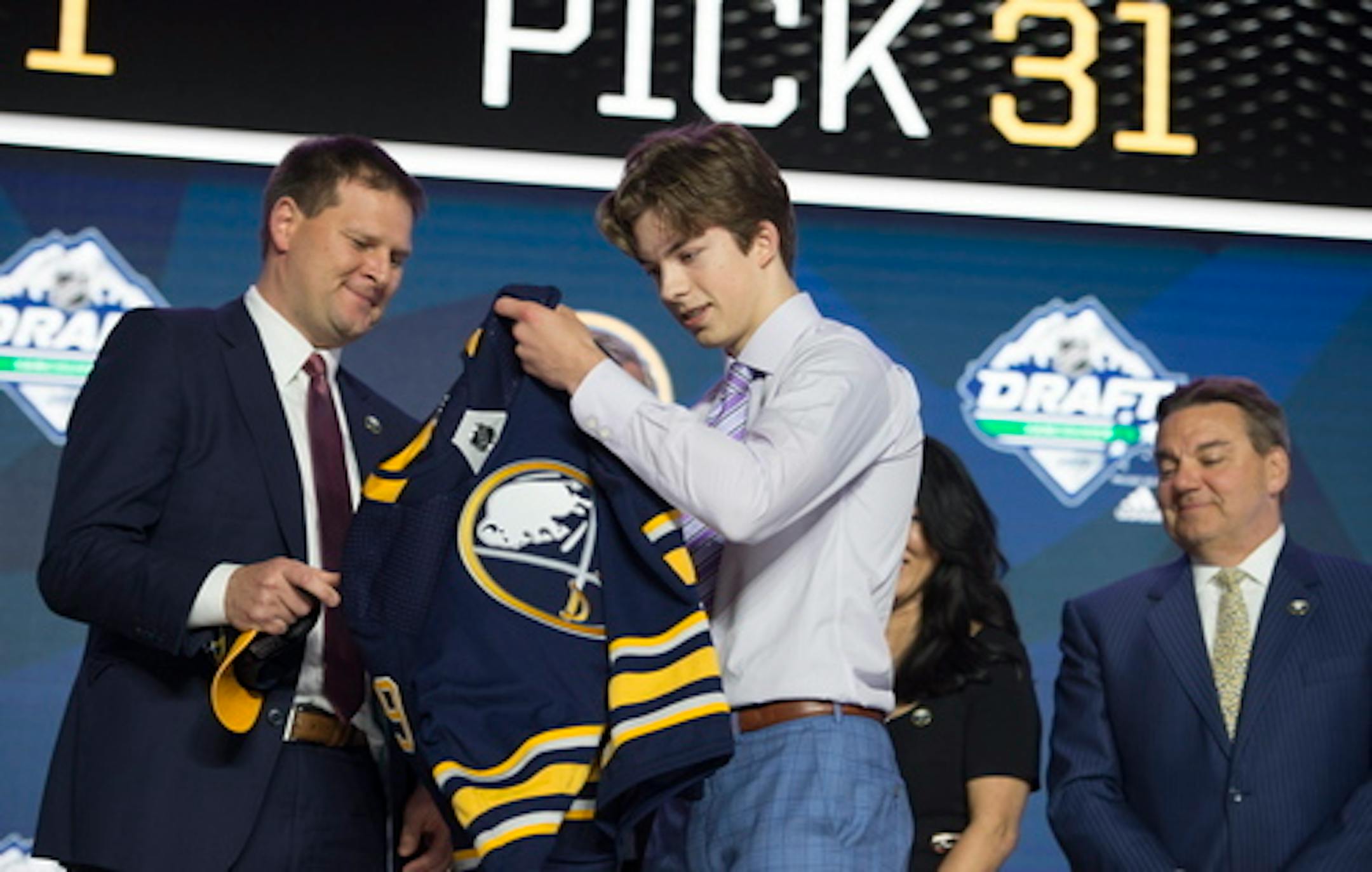 Ryan Johnson puts on a Buffalo Sabres jersey during the first round of the NHL hockey draft Friday, June 21, 2019, in Vancouver, British Columbia. (Jonathan Hayward/The Canadian Press via AP)