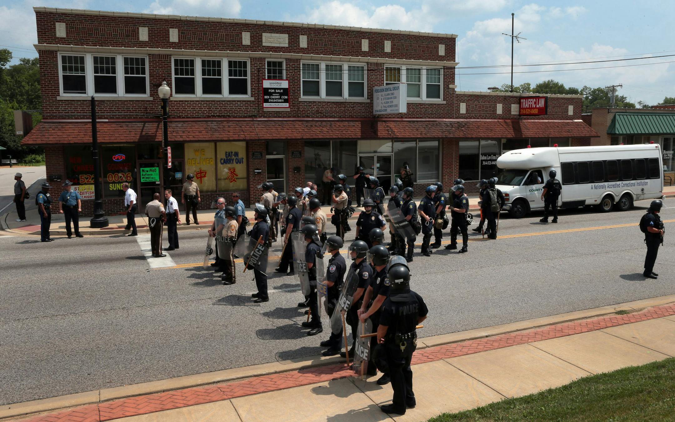 Riot police officers moved down S. Florissant Road in downtown Ferguson, Mo., on Monday, Aug. 11, 2014, as they move demonstrators from the police station after Saturday's police shooting of Michael Brown. (AP Photo/St. Louis Post-Dispatch, Robert Cohen) ORG XMIT: MIN2014081910130836
