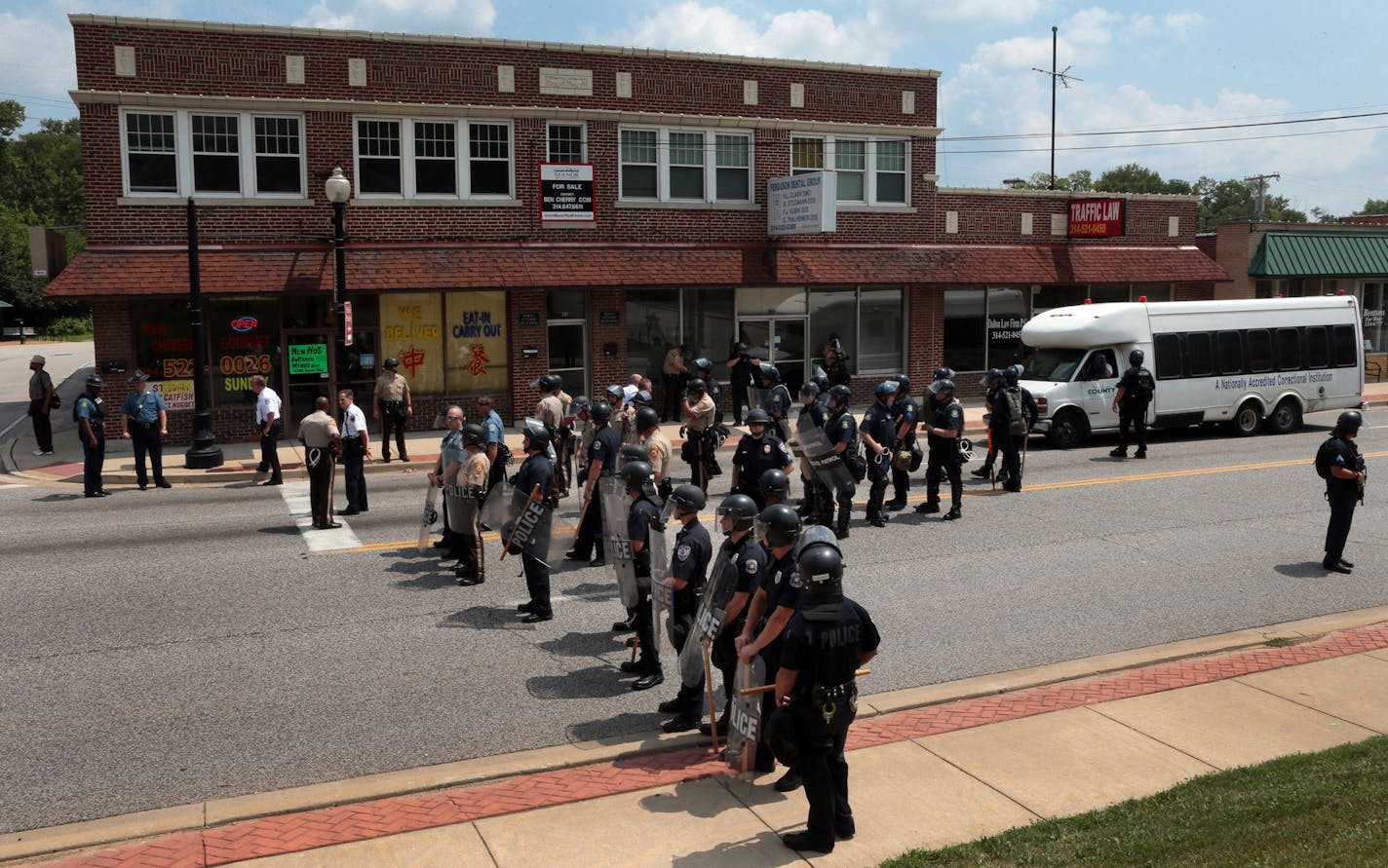 Riot police officers moved down S. Florissant Road in downtown Ferguson, Mo., on Monday, Aug. 11, 2014, as they move demonstrators from the police station after Saturday's police shooting of Michael Brown. (AP Photo/St. Louis Post-Dispatch, Robert Cohen) ORG XMIT: MIN2014081910130836