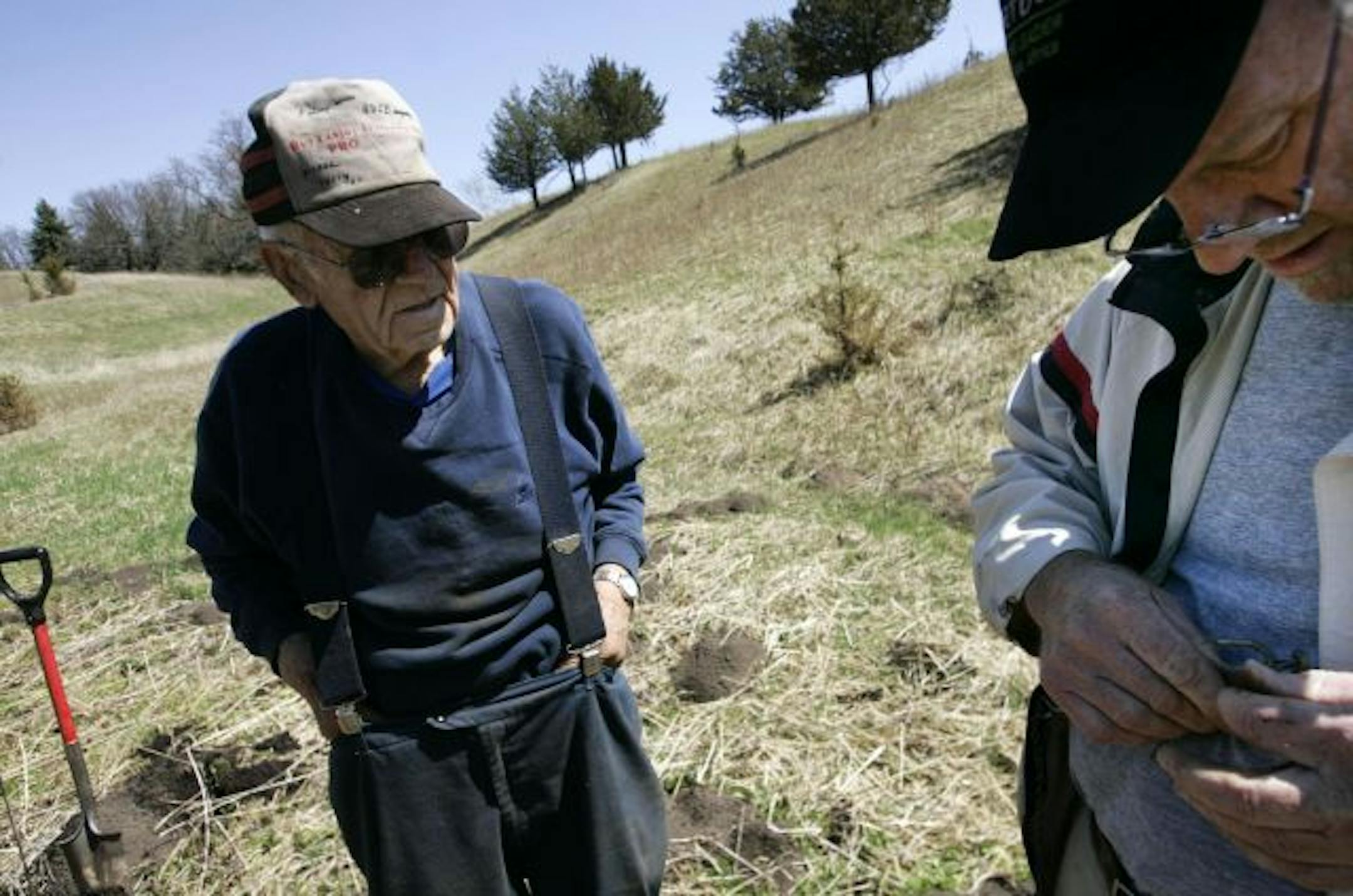 Before his retirement, Bert Arkman, left, is showing Voedisch how to set a gopher trap himself. But it's also becoming a competitive business: Last year, May Township required hunters to sign a form that the animals were from the area, and officials checked with landowners.