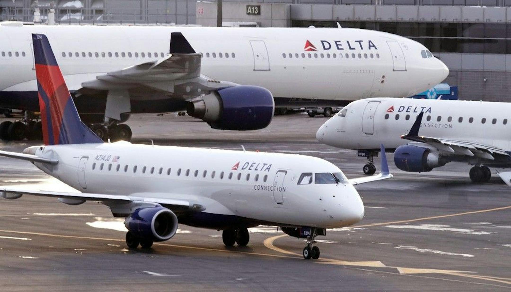 A Delta Connection Embraer 175 aircraft, foreground, taxis to a gate at Logan International Airport in Boston, Monday, Jan. 8, 2018.