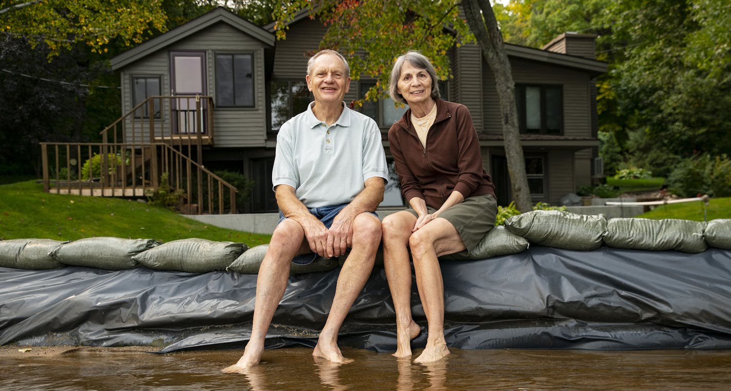 Cheryl and Bob Koll posed on their sandbag wall in Lake Shamineau in front of their home of 50 years, which they are fighting to save.