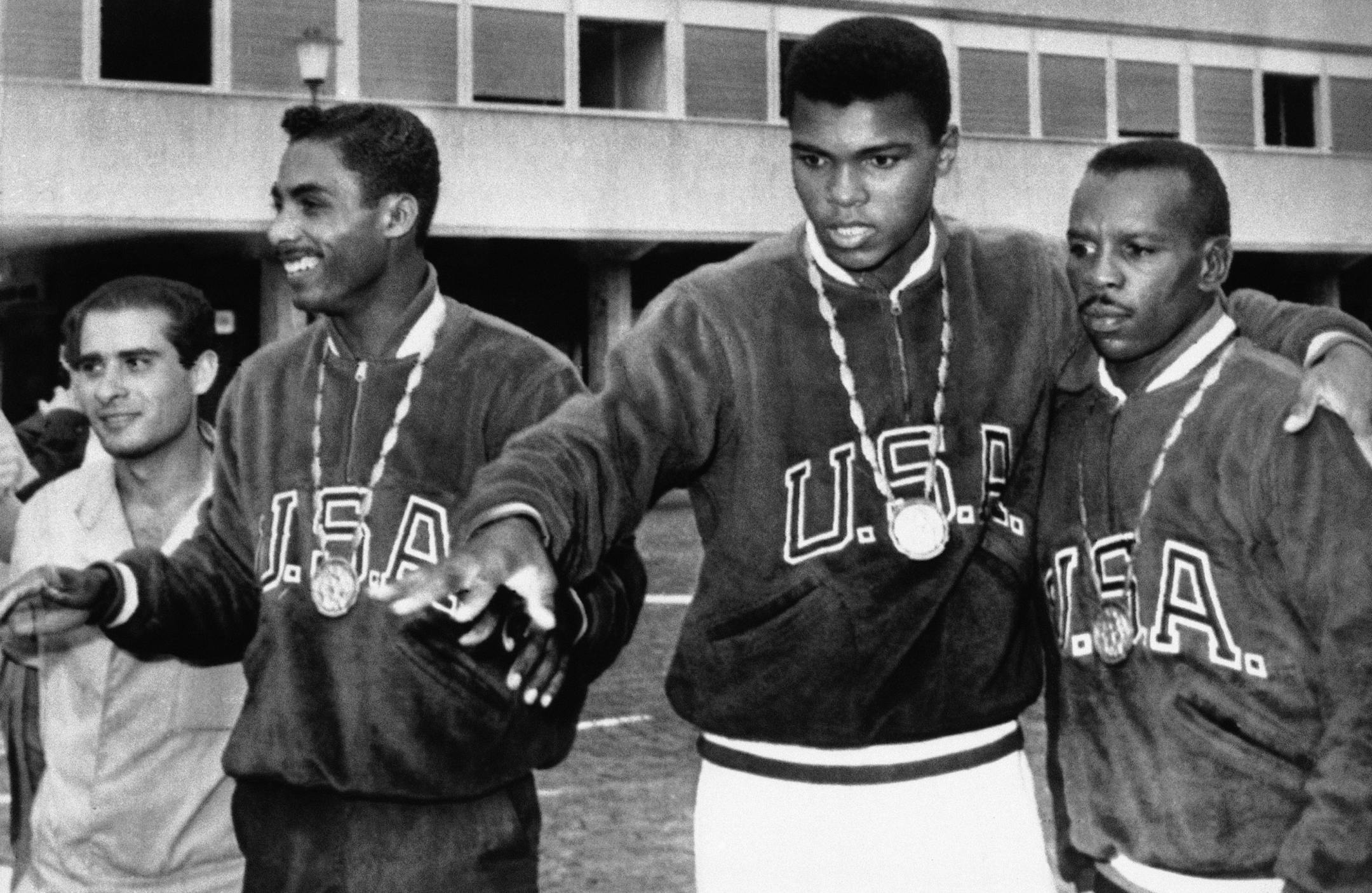 A trio of U.S. boxers wear gold medals at the Olympic village in Rome, Sept. 6, 1960. From the left are: Wilbert McClure of Toledo, Ohio, light middleweight; Cassius Clay of Louisville, Kentucky, light heavyweight; and Edward Crook of Fort Campbell, Kentucky, middleweight. (AP Photo) ORG XMIT: APHS281682