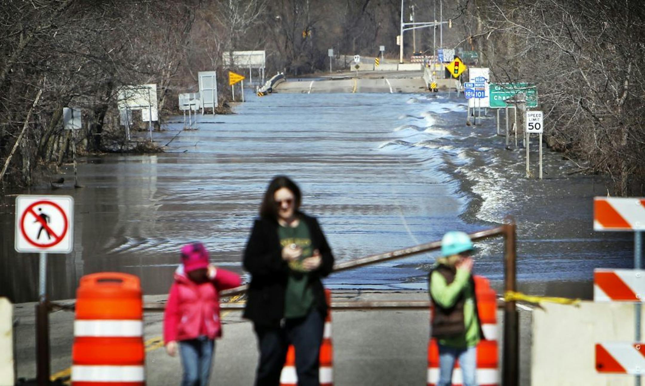 Despite flood waters receding, the swollen Minnesota River still flowed heavily over a closed portion of Highway 101 as pedestrians took in the sights.