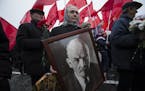 A woman with a portrait of Lenin walks with the Communist Party members and supporters to put flowers at the Tomb of Soviet founder Vladimir Lenin, at