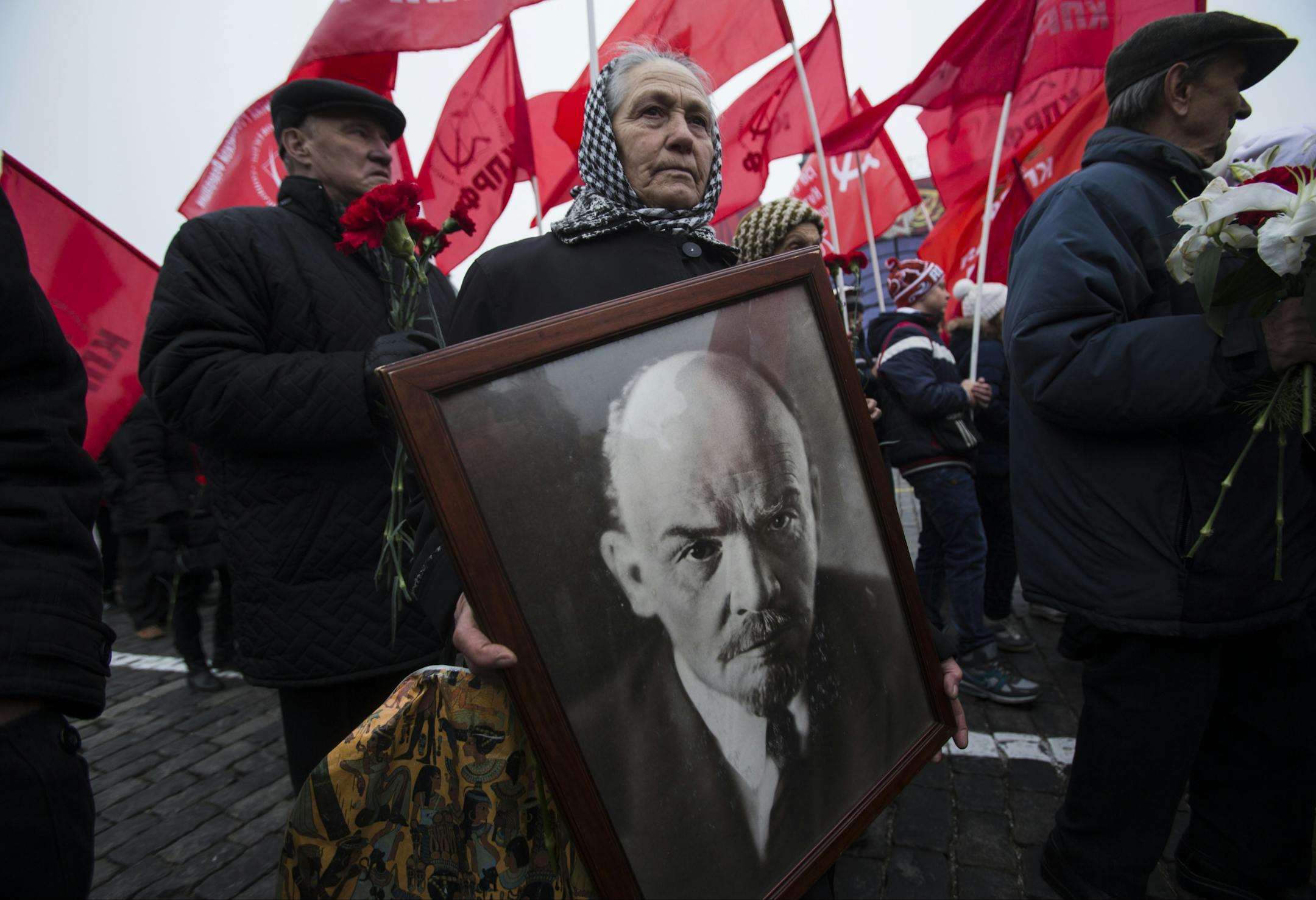 A woman with a portrait of Lenin walks with the Communist Party members and supporters to put flowers at the Tomb of Soviet founder Vladimir Lenin, at Moscow's Red Square on Thursday, Nov. 6, 2014 to mark the anniversary of the Nov. 7, 1917 Bolshevik revolution, which is not a public holiday in Russia any more.