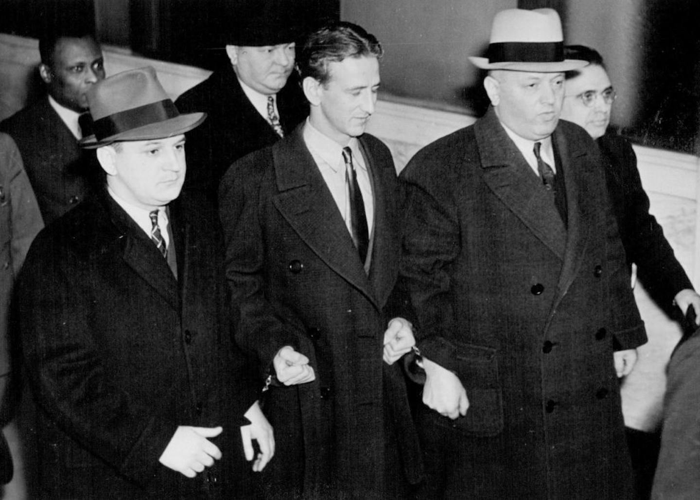 February 8, 1938 Ross Kidnaper to Be Tried March 21 -- John Henry Seadlund, Center, surrounded by deputy U. S. Marshals and G-Men, Being brought into federal court in Chicago for a hearing at which arraignment was set for Feb. 28, and the date of his trial for the kidnap-murder of Charles S. Ross of Chicago was set for March 21. If he pleads guilty Feb. 28, the trial will be necessary to determine whether he gets life in Jail or the electric chair. ACME