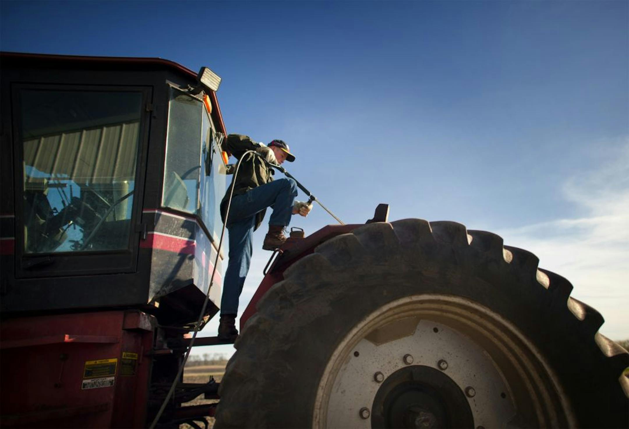 14-year-old ag student washes a tractor.