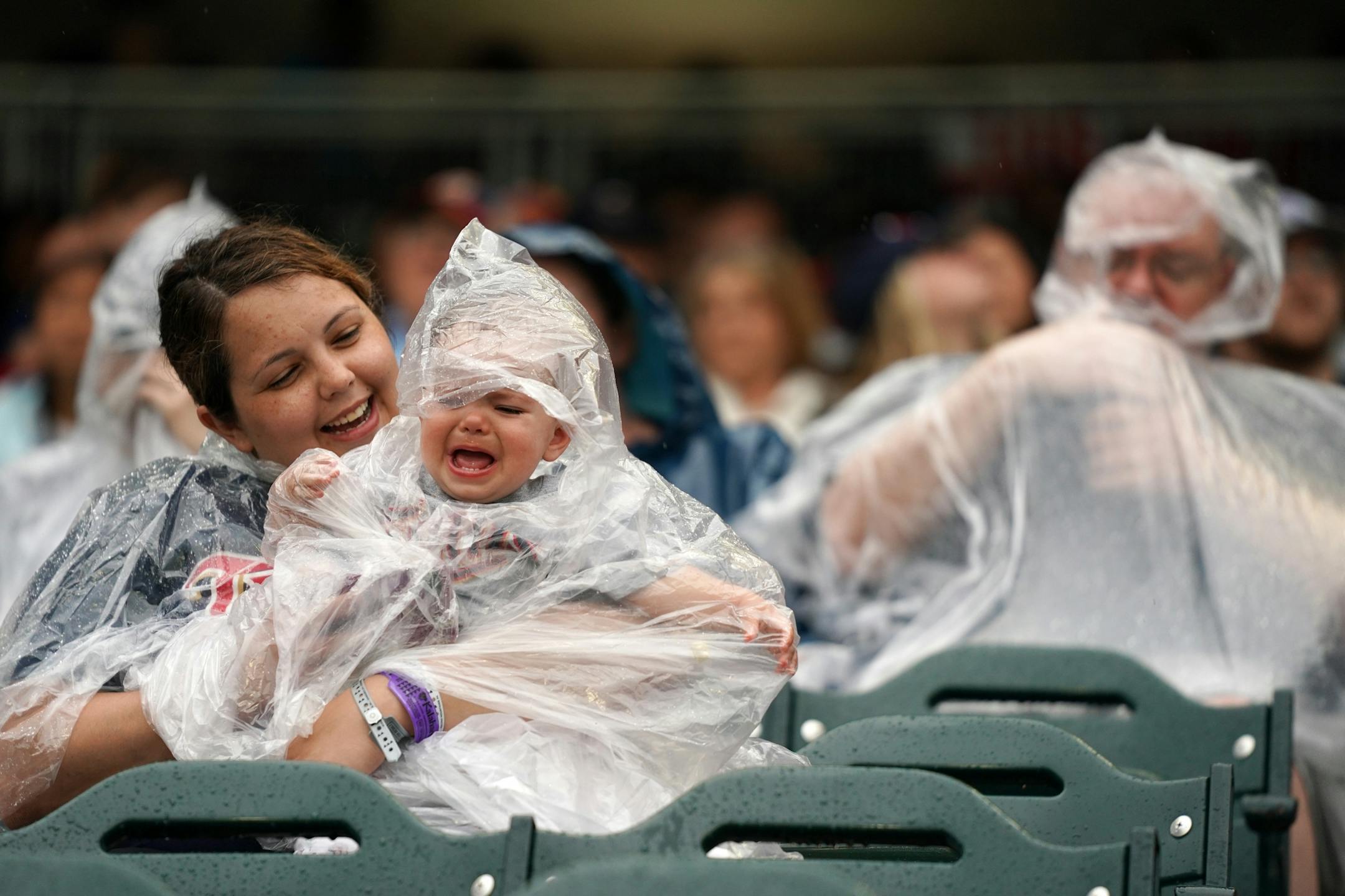 Susan Dodd of Sioux City, Iowa tried to calm her daughter, Saylor, 1, as she fought with her plastic poncho during a rain delay Friday at Target Field.