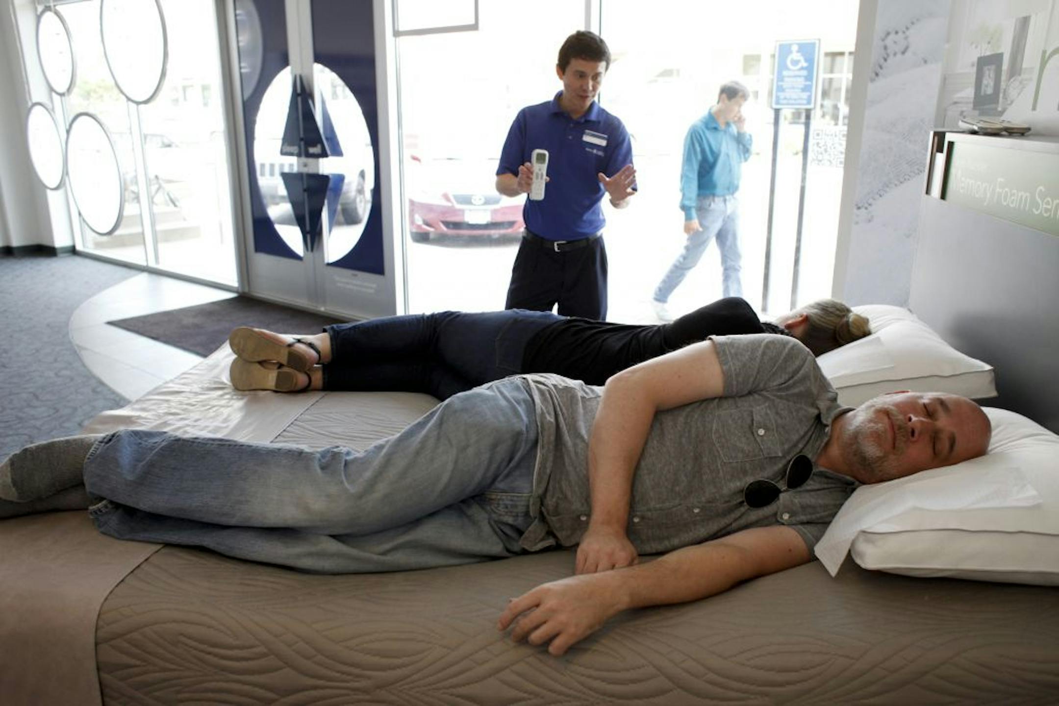 Peter Thill relaxes into a new M9 memory foam mattress as store salesman Vince Meyer talks to Thill's wife about the various bed settings at a Sleep Number store in Edina, Minn. on Friday July 27, 2012.