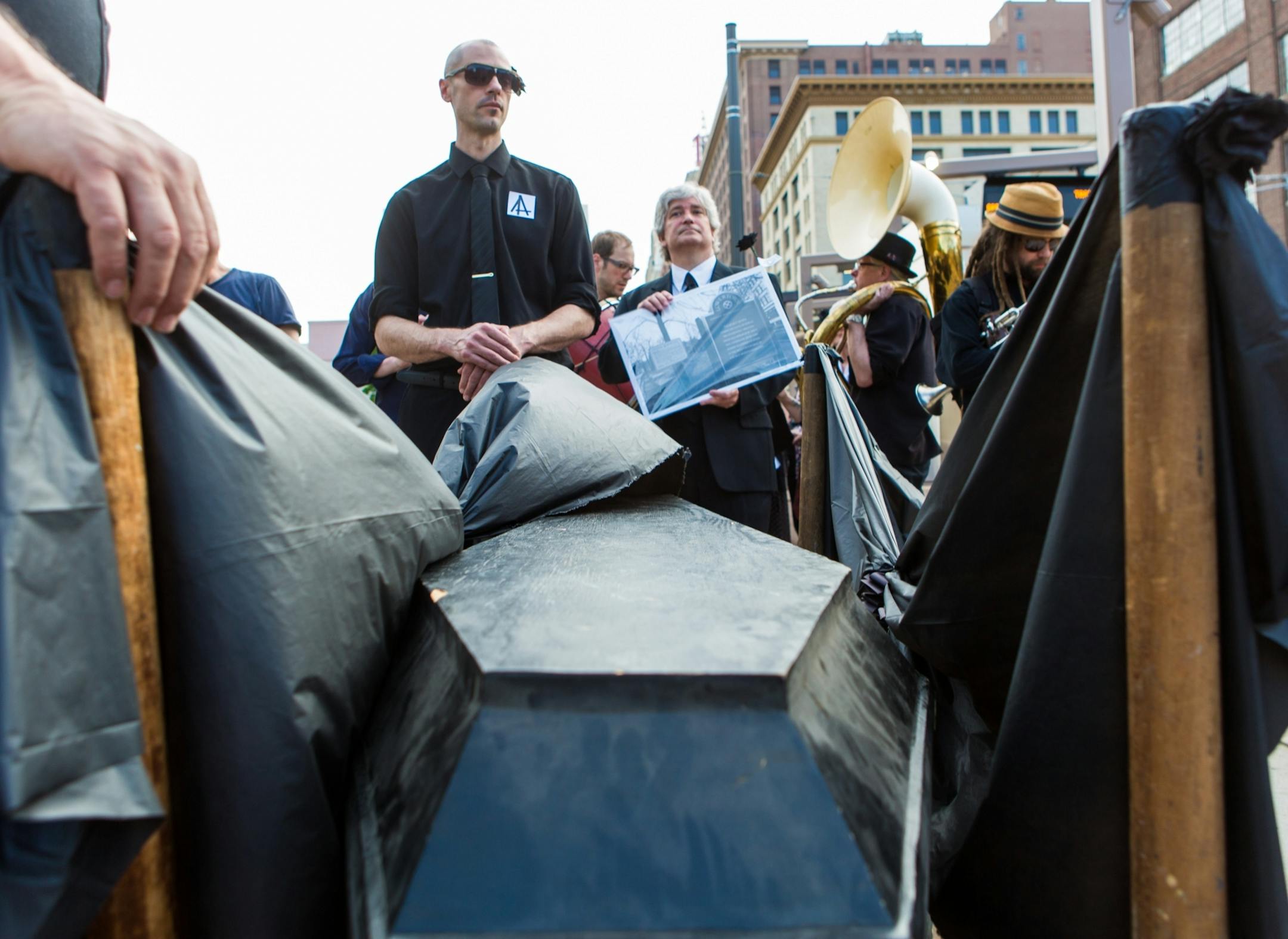 Former Jax building tenants and Lowertown arts supporters stand near the coffin representing the Jax Building at the Union Depot Friday evening.