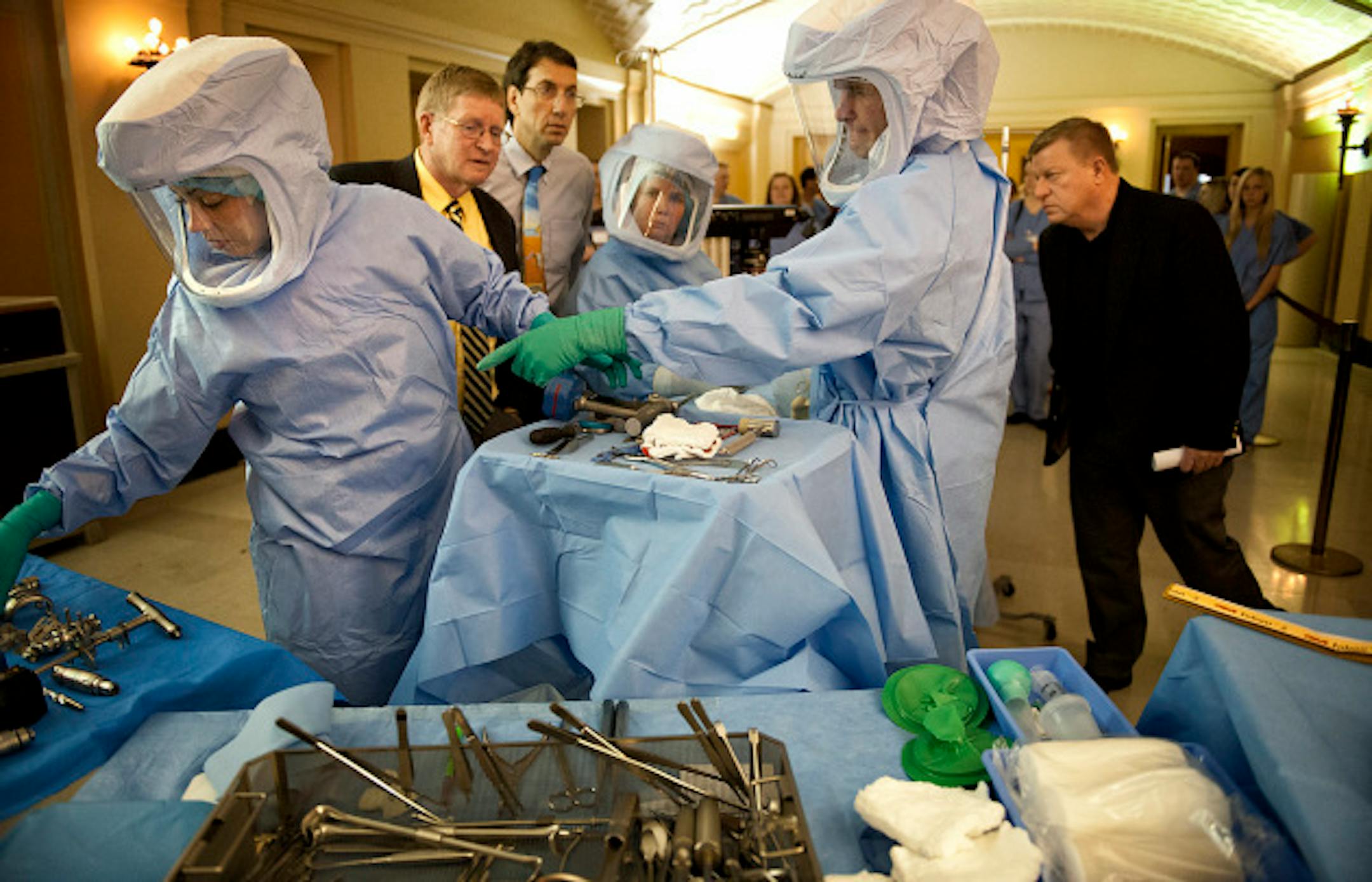 Representatives Paul Anderson, left, and Mike Sundin, right watched the mock knee replacement intently.  Sundin's father recently had the procedure and Sundin himself has been told he needs one soon.   Surgical technologists and surgical technology students participated in a mock knee replacement procedure in the Great Hall of the Capitol Thursday, April 11, 2013 to bring attention to to bills that would ensure standards for the now unregulated profession.      ]   GLEN STUBBE * gstubbe@startribune.com