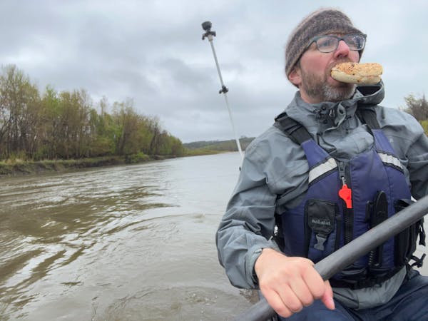 Scott Miller gets in some nourishment Sunday during a rainy shakedown paddle on the Minnesota River between New Ulm and Henderson.