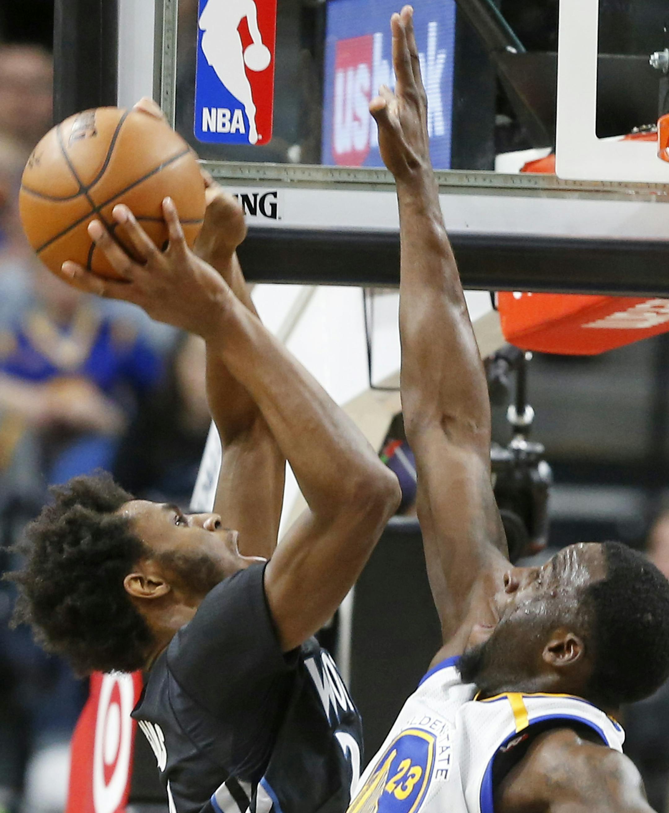 Minnesota Timberwolves' Andrew Wiggins, left, shoots over Golden State Warriors' Draymond Green during the second half of an NBA basketball game Friday, March 10, 2017, in Minneapolis. Wiggins led the Timberwolves with 24 points in their 103-102 win. (AP Photo/Jim Mone)