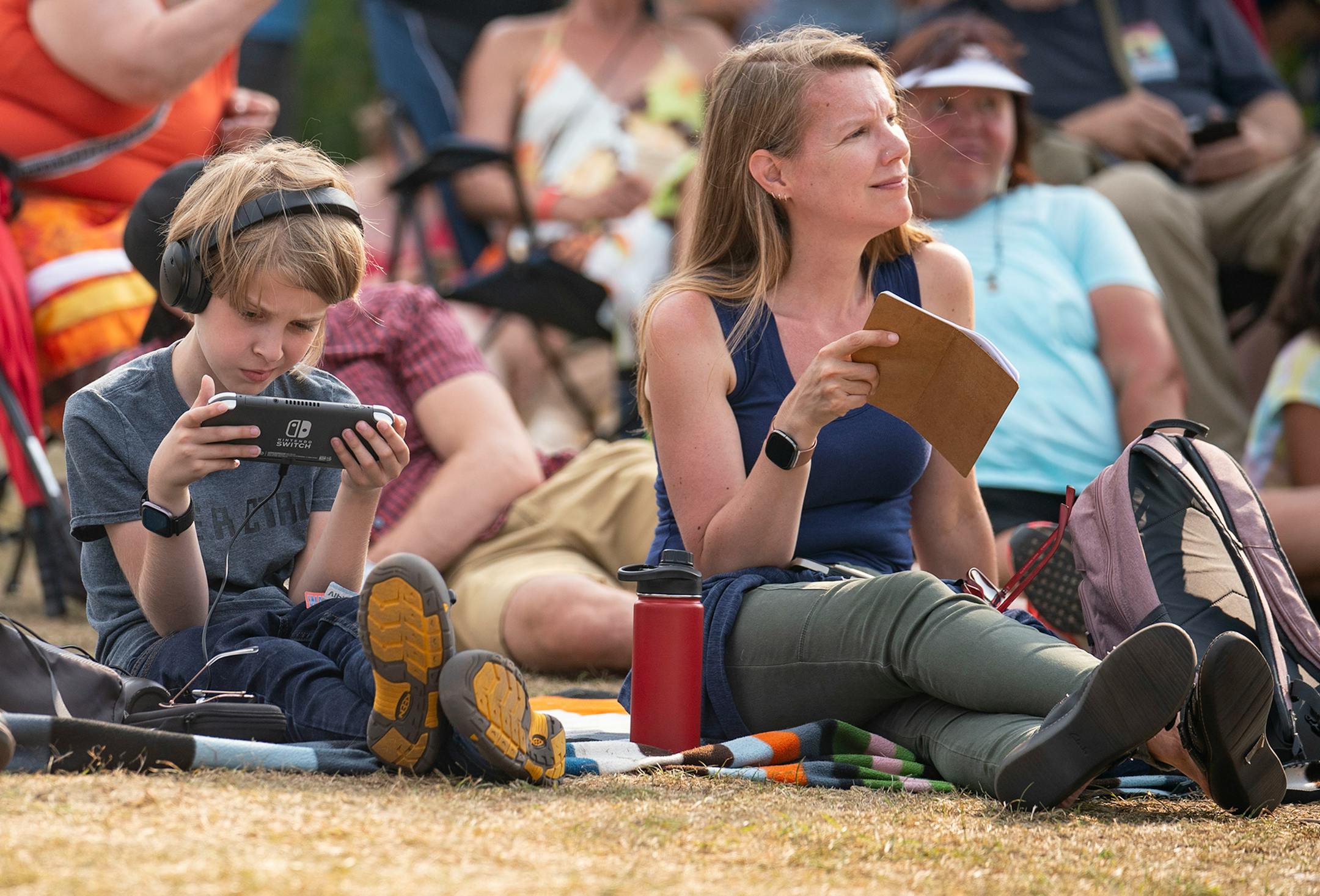 A young boy played on his Nintendo Switch while Keith Secola performed on the side stage at the Water is Life Festival on Wednesday.