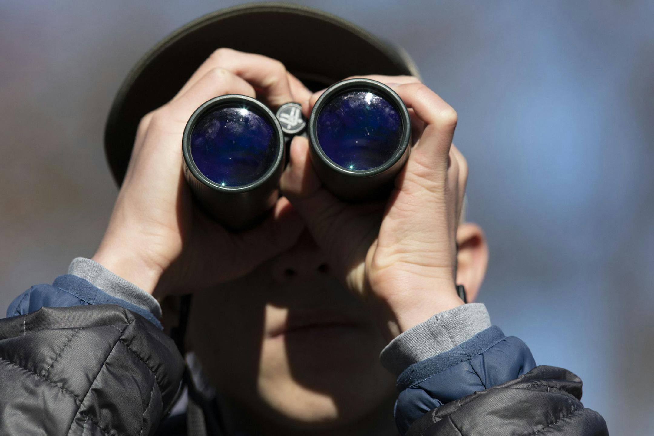 Isoo O'Brien looks for birds with his binoculars in Jackson Park.