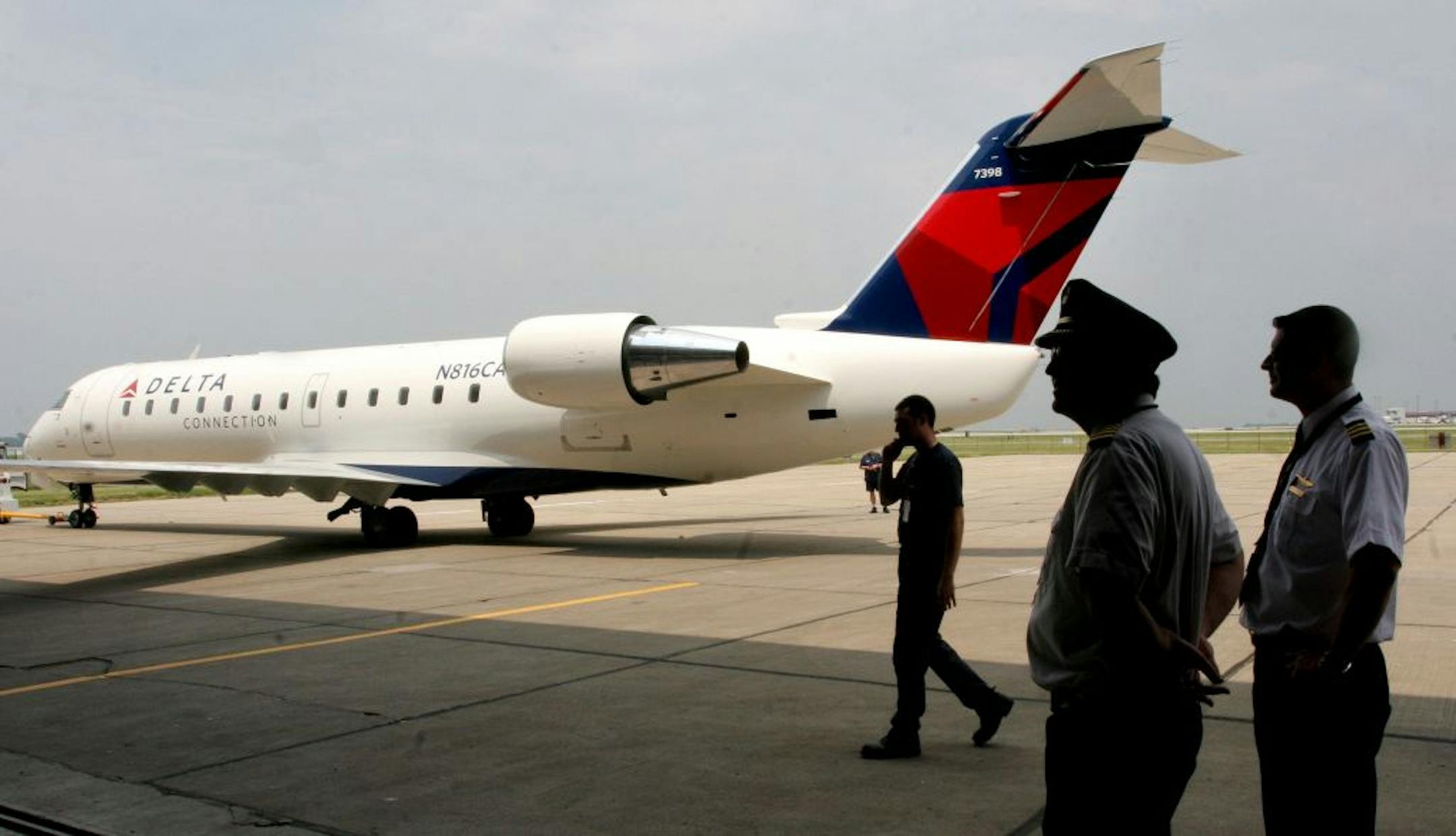 FILE - In this May 24, 2007 file photo, Comair employees look at the new logo on a Comair plane at the Cincinnati-Northern Kentucky Airport in Hebron, Ky. Delta Air Lines said Friday, July 27, 2012, it will close its regional carrier Comair at the end of September as it switches more of its flying to bigger jets. Delta, which is based in Atlanta, has about 350 regional jets and plans to reduce that to 125 within two years. Operating regional carriers has become more expensive while customers hav