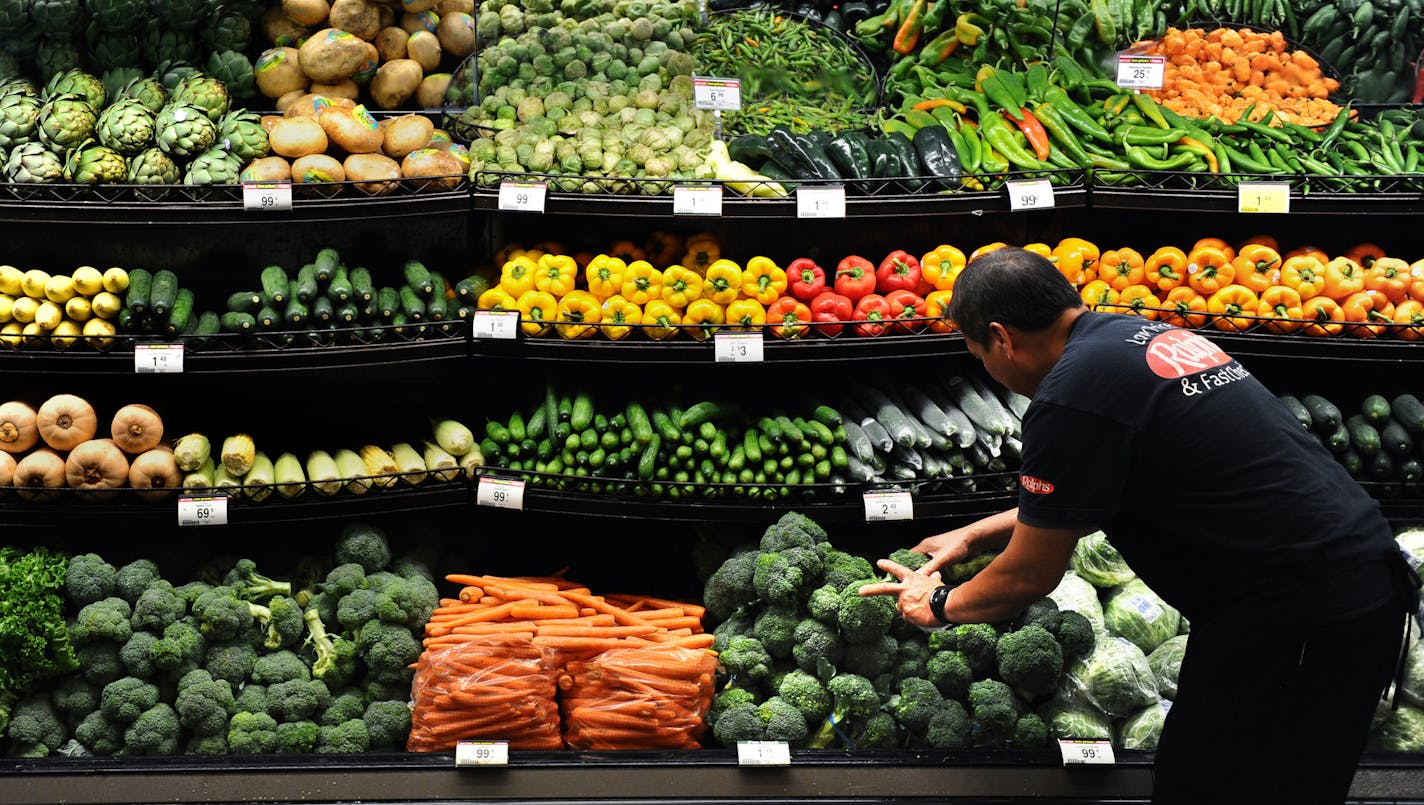 Produce clerk Frank Duenas arranged vegetables at a grocery store in downtown Los Angeles. Declining food prices are problem for grocery retailers like Supervalu.