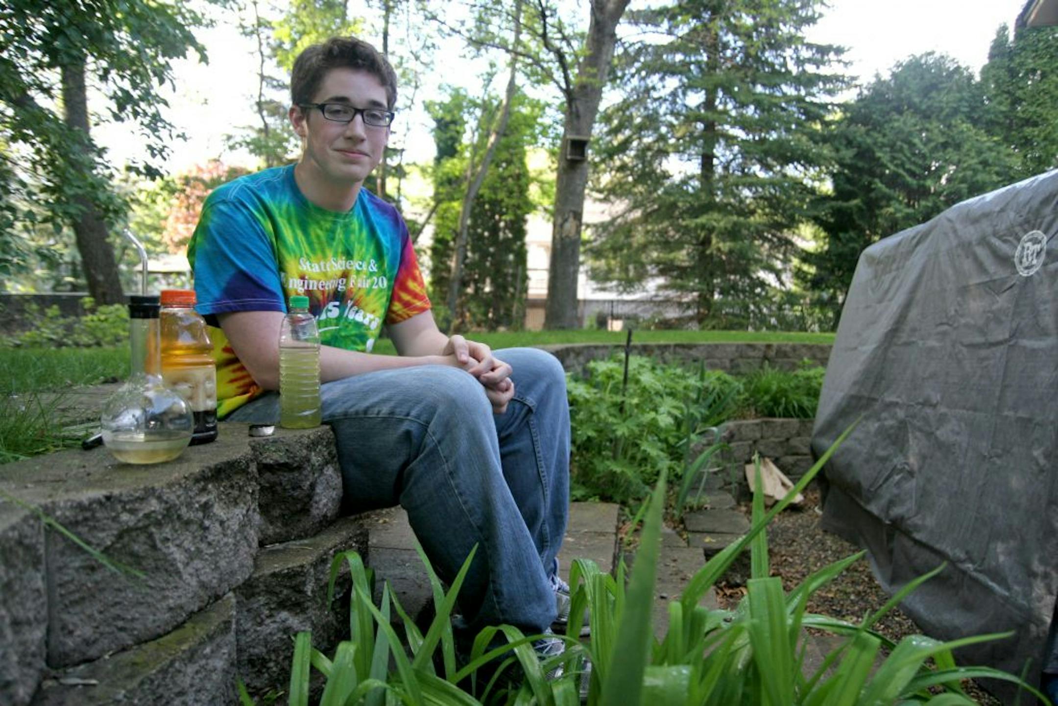 Elk River High School sophomore Josh Wolf works out of a portable garage in his back yard. It was a Christmas gift from his family last year. He's flanked by a vial of gasoline he made from recycled plastic bags, a jug of the glycerine that's a byproduct of the algae conversion, and a bottle of algae-derived biodiesel. Photo: Maria Baca/Star Tribune
