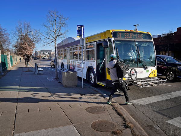 A rider with a bicycle pulls the bike off a rack on a Metro Transit route 21 bus traveling west along Lake Street at Cedar Ave. S. Wednesday in Minnea