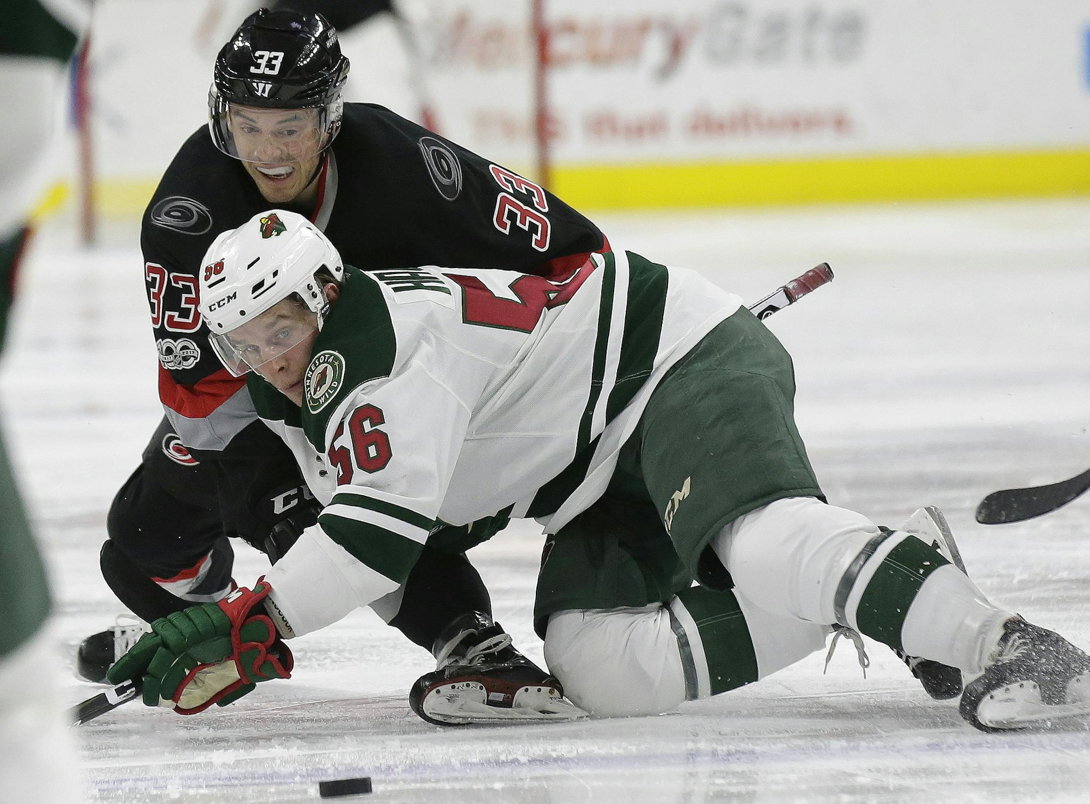 Carolina Hurricanes' Derek Ryan (33) and Minnesota Wild's Erik Haula (56), of Finland, struggle for possession of the puck during the second period of an NHL hockey game in Raleigh, N.C., Thursday, March 16, 2017. (AP Photo/Gerry Broome)