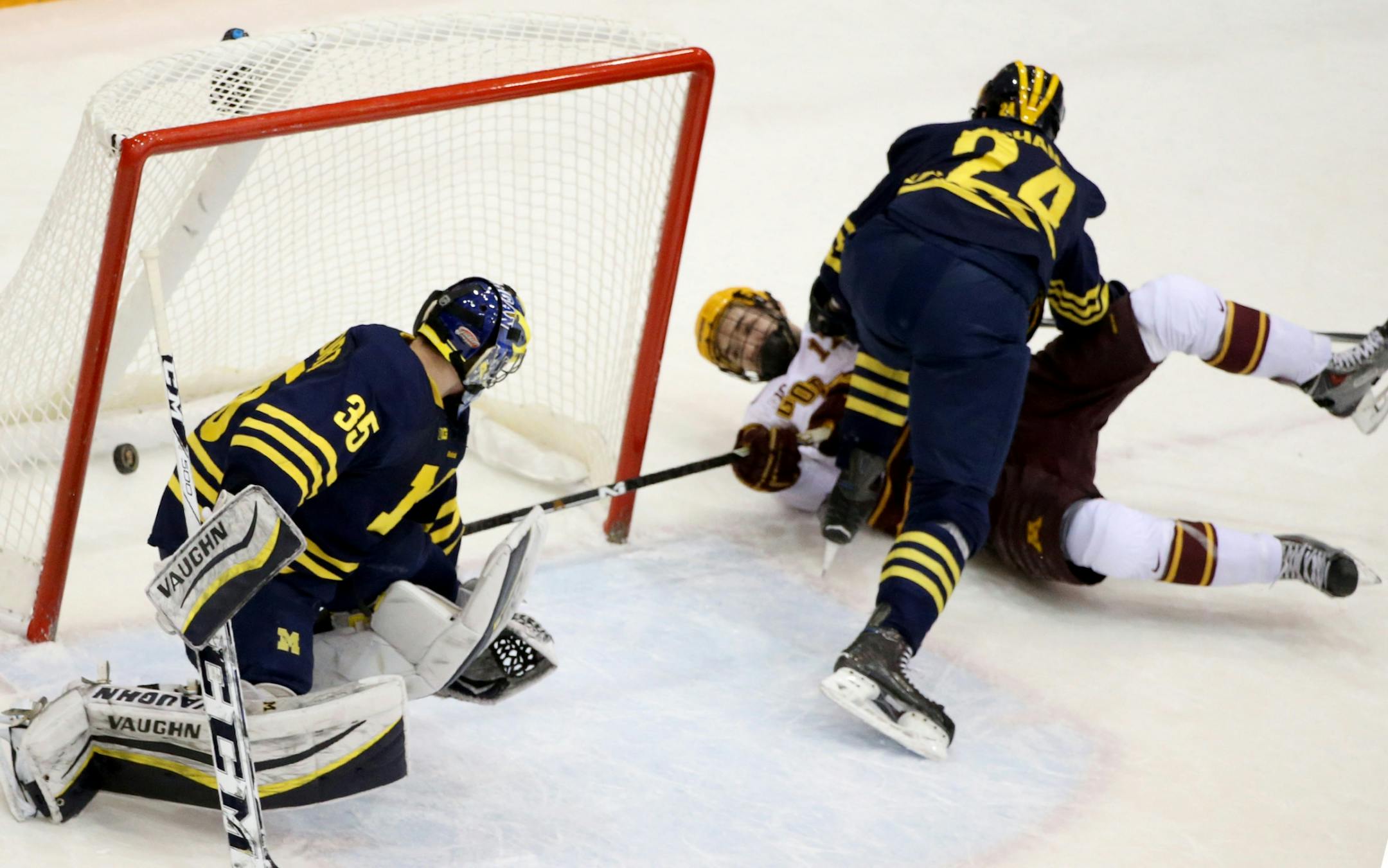 While on his back, the University of Minnesota's Seth Ambroz (17) scores past University of Michigan goalie Zach Nagelvoort (35) during the first period Friday, Feb. 13, 2015.