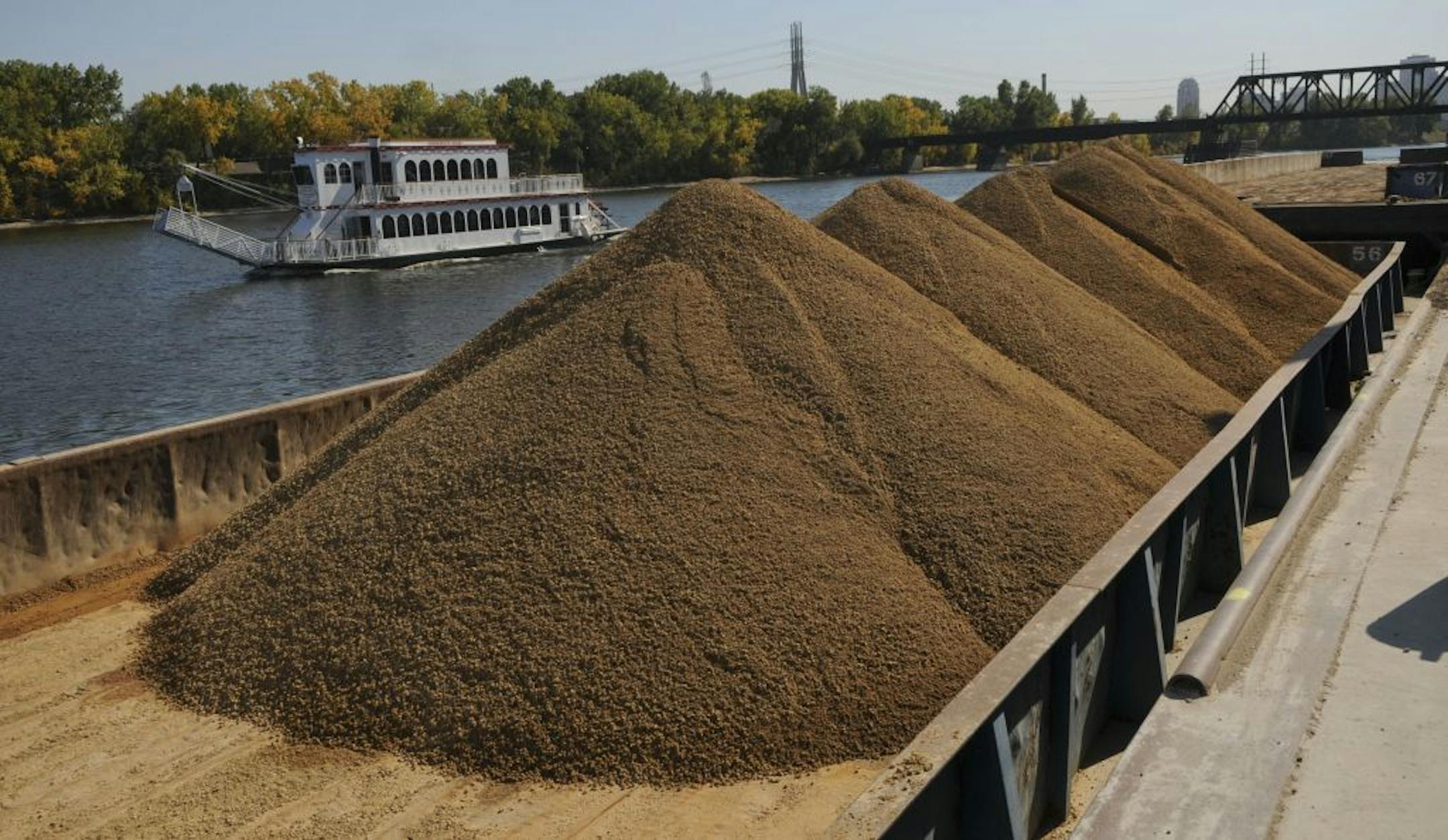 The Minneapolis Queen Paddle boat passes by a barge loaded full of gravel at Aggregate Industries on Monday 10/3/2011 in Minneapolis, Minn.The threat of asian carp threatens the future of the St. Anthony Falls locks. Aggregate Industries is one of the operations that still operates north of the locks..