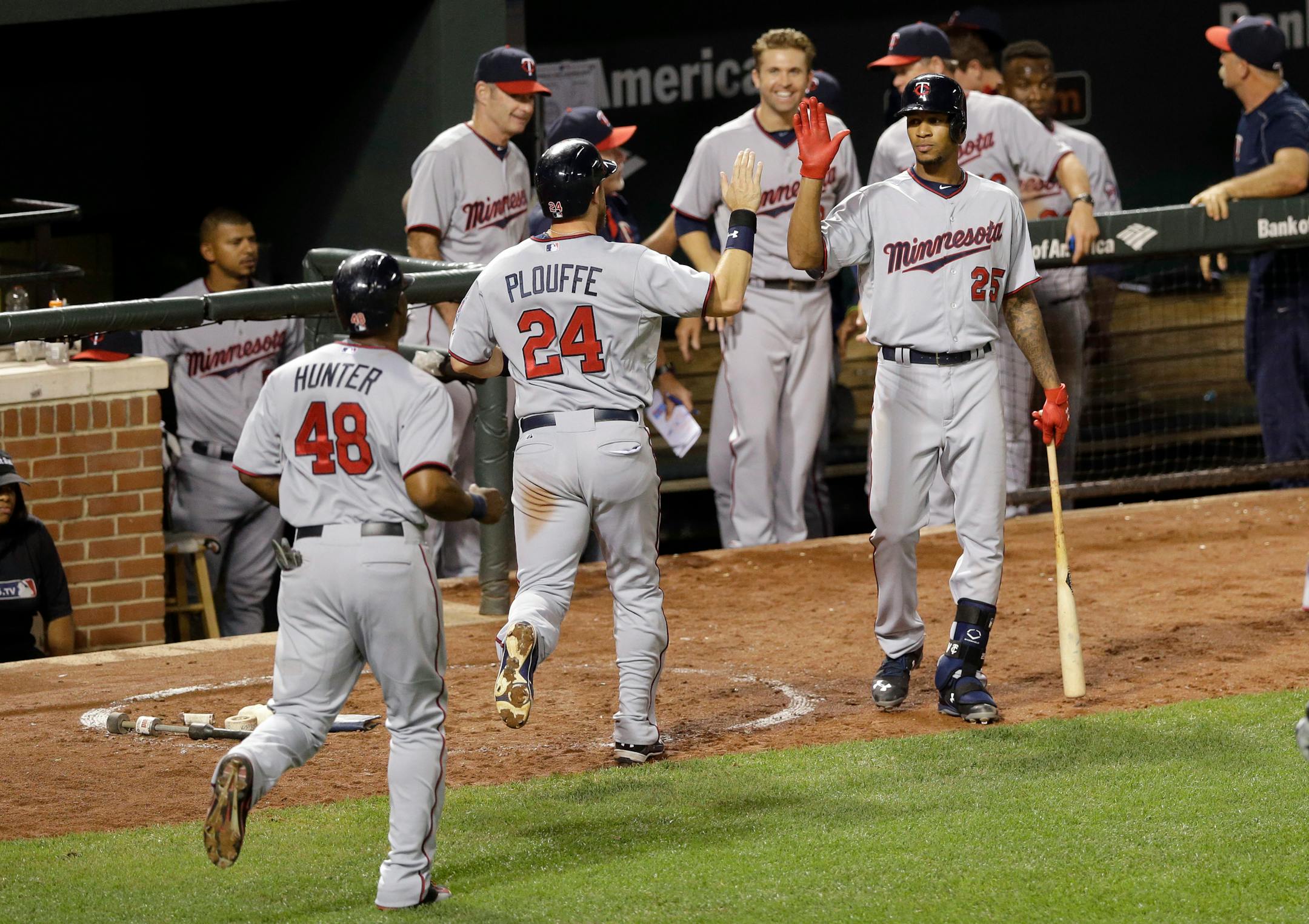 Minnesota Twins' Byron Buxton (25) high-fives teammates Trevor Plouffe (24) and Torii Hunter (48) after they scored on a single by Kurt Suzuki during the eighth inning of a baseball game against the Baltimore Orioles, Friday, Aug. 21, 2015, in Baltimore. Minnesota won 4-3.