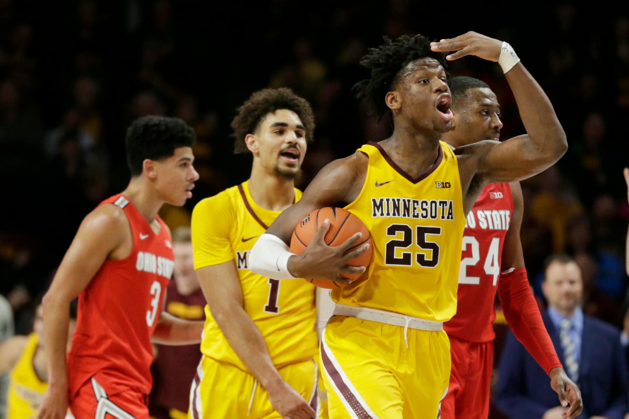 Daniel Oturu and Tre' Williams celebrate as Ohio State's D.J. Carton (3) and forward Andre Wesson (24) leave the court after the Gophers' upset win in December.