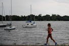 A runner jogs past a boat launch area near the main beach of Lake Nokomis Friday afternoon.