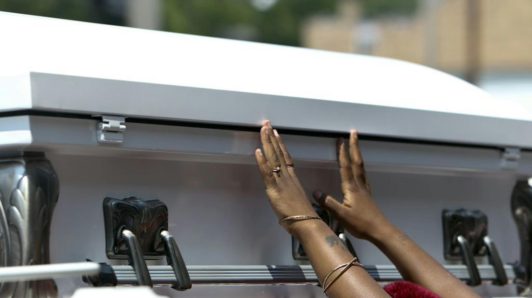 Christina Banks, reaches up to touch the coffin holding her slain son Nizzel George, 5, following services Tuesday, July 3, 2012, at Shiloh Temple in Minneapolis, MN .