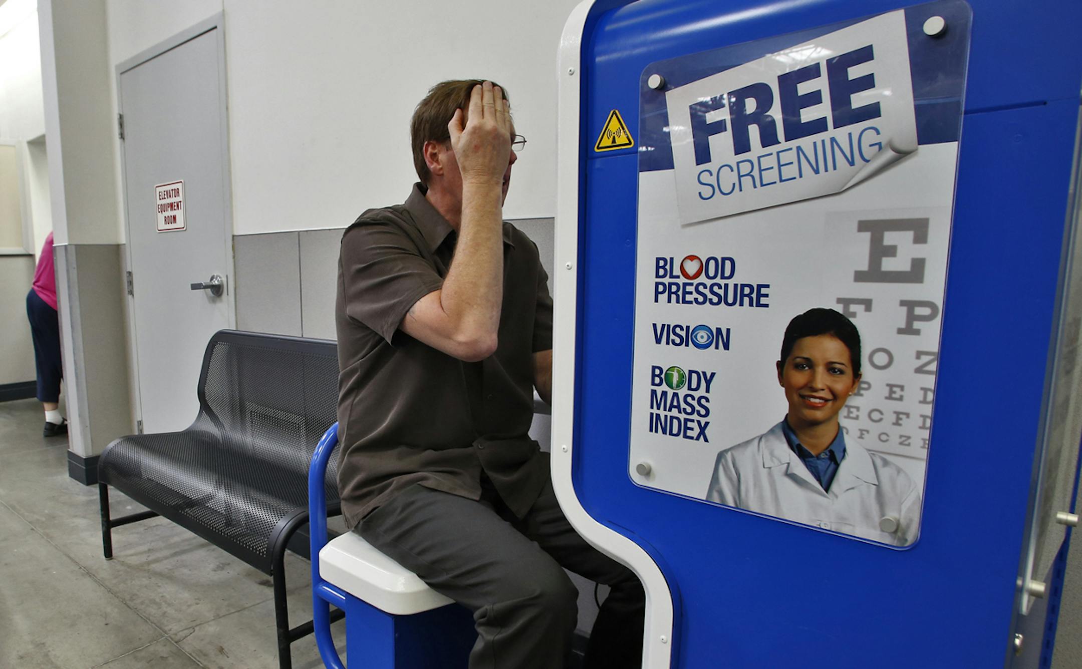 Folks using the solohealth kiosk near the pharmacy at Sam's Club in St. Louis Park. The machine offers six programs to test blood pressure, sight, body mass, etc. Here Carter Anderson, Sam's Club optical manager, uses the machine to update his monthly checkup. Anderson performed the eye test. (MARLIN LEVISON/STARTRIBUNE(mlevison@startribune.com (cq )