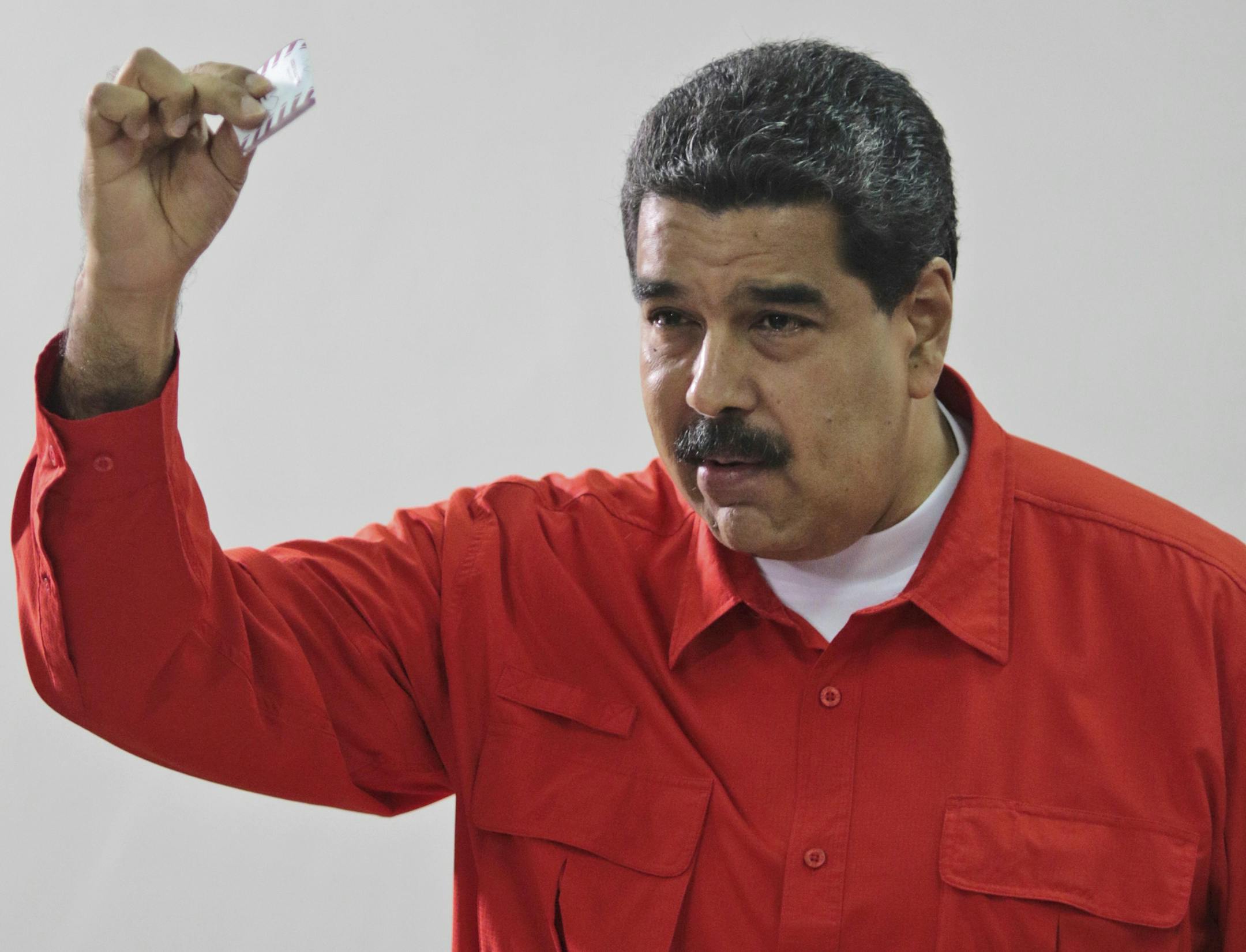 In this photo released by Miraflores Press Office, Venezuela's President Nicolas Maduro shows his ballot after casting a vote for a constitutional assembly in Caracas, Venezuela on Sunday, July 30, 2017. Maduro asked for global acceptance on Sunday as he cast an unusual pre-dawn vote for an all-powerful constitutional assembly that his opponents fear he'll use to replace Venezuelan democracy with a single-party authoritarian system. (Miraflores Press Office via AP)