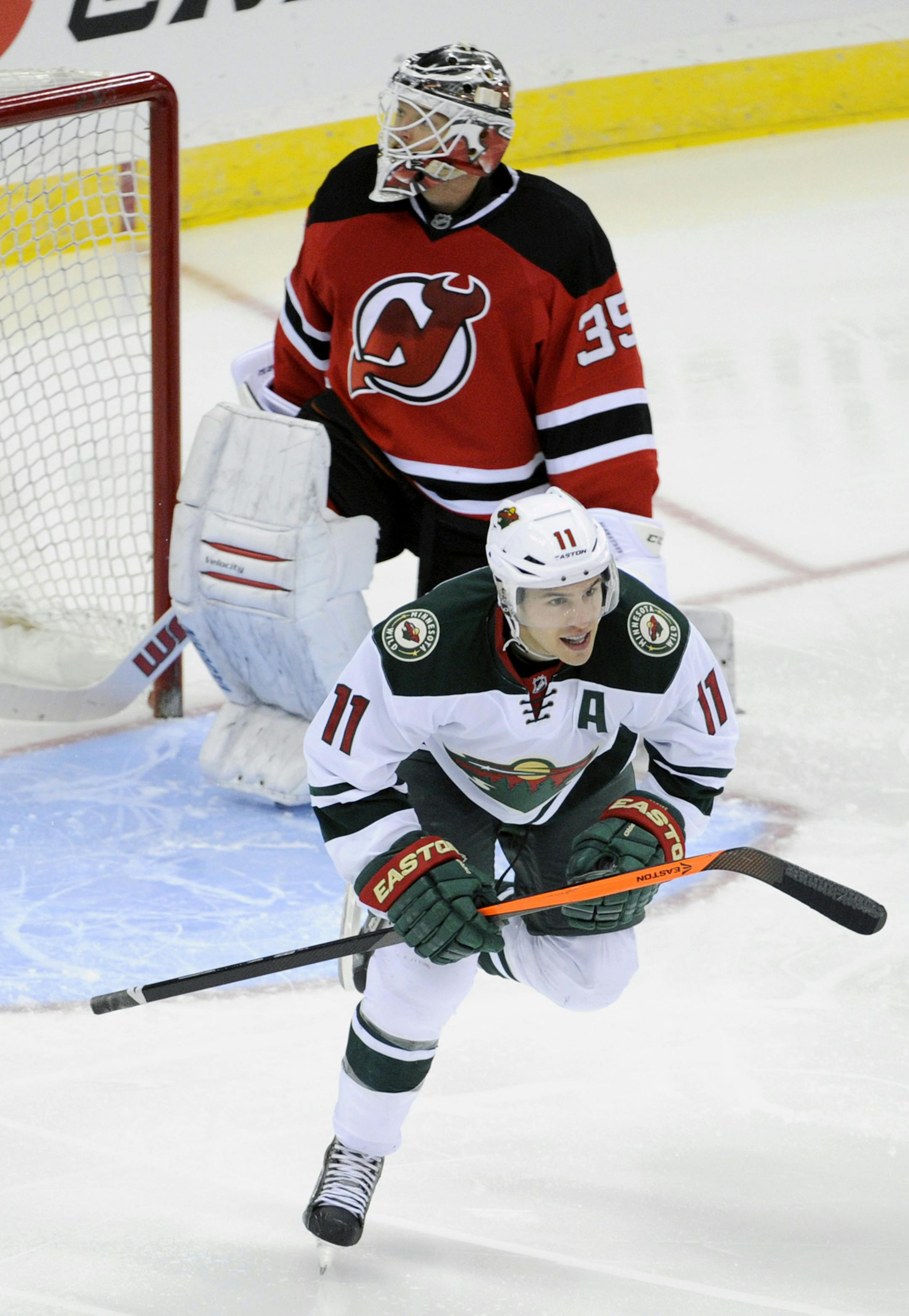 Minnesota Wild's Zach Parise (11) celebrates his goal as New Jersey Devils goaltender Cory Schneider reacts stands near in the third period of an NHL hockey game Thursday, March 20, 2014, in Newark, N.J. The Devils won 4-3 in overtime.(AP Photo/Bill Kostroun)