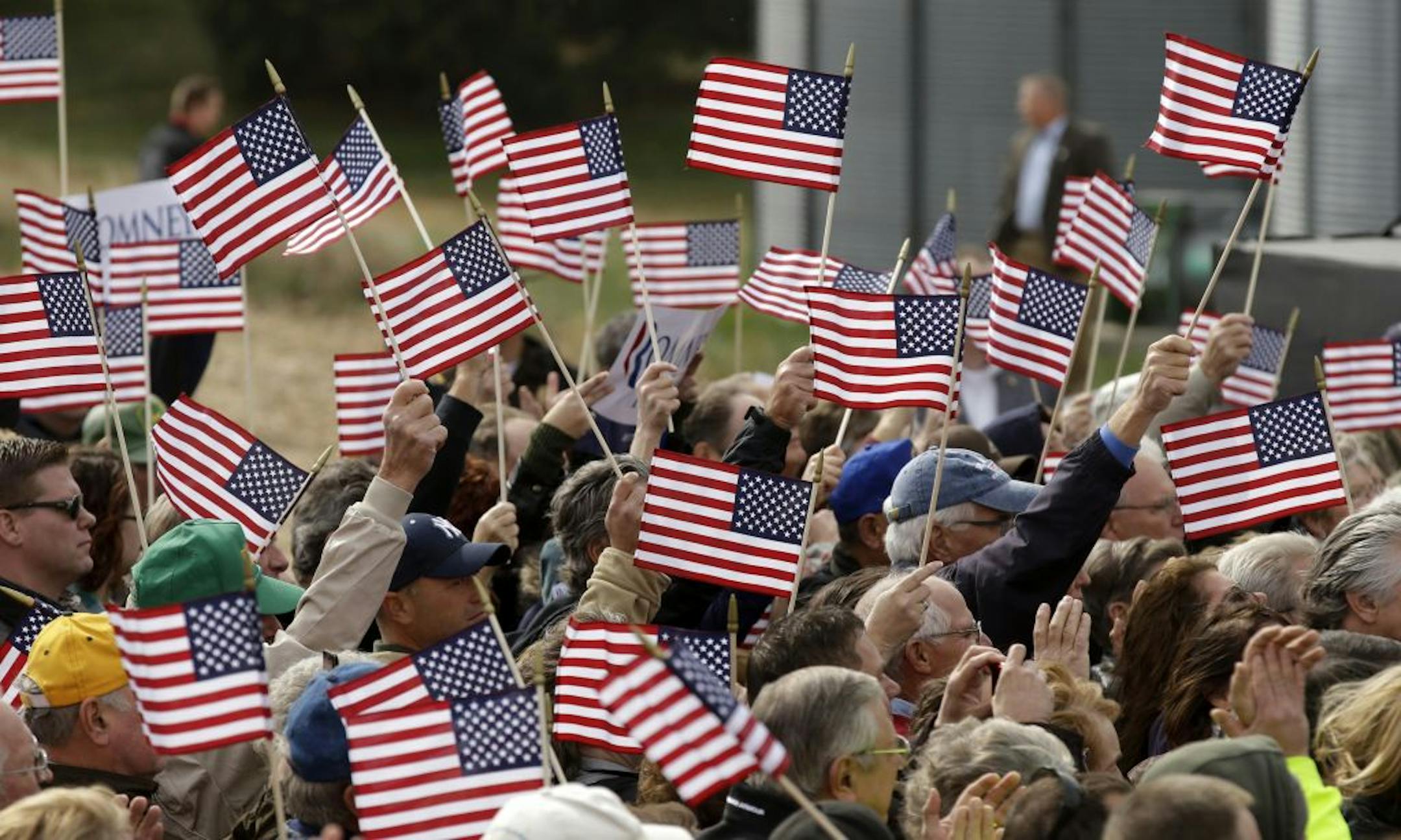 Supporters wave flags as Republican presidential candidate, former Massachusetts Gov. Mitt Romney speaks during a campaign stop at the Koch Family Farm, Tuesday, Oct. 9, 2012, in Van Meter, Iowa.