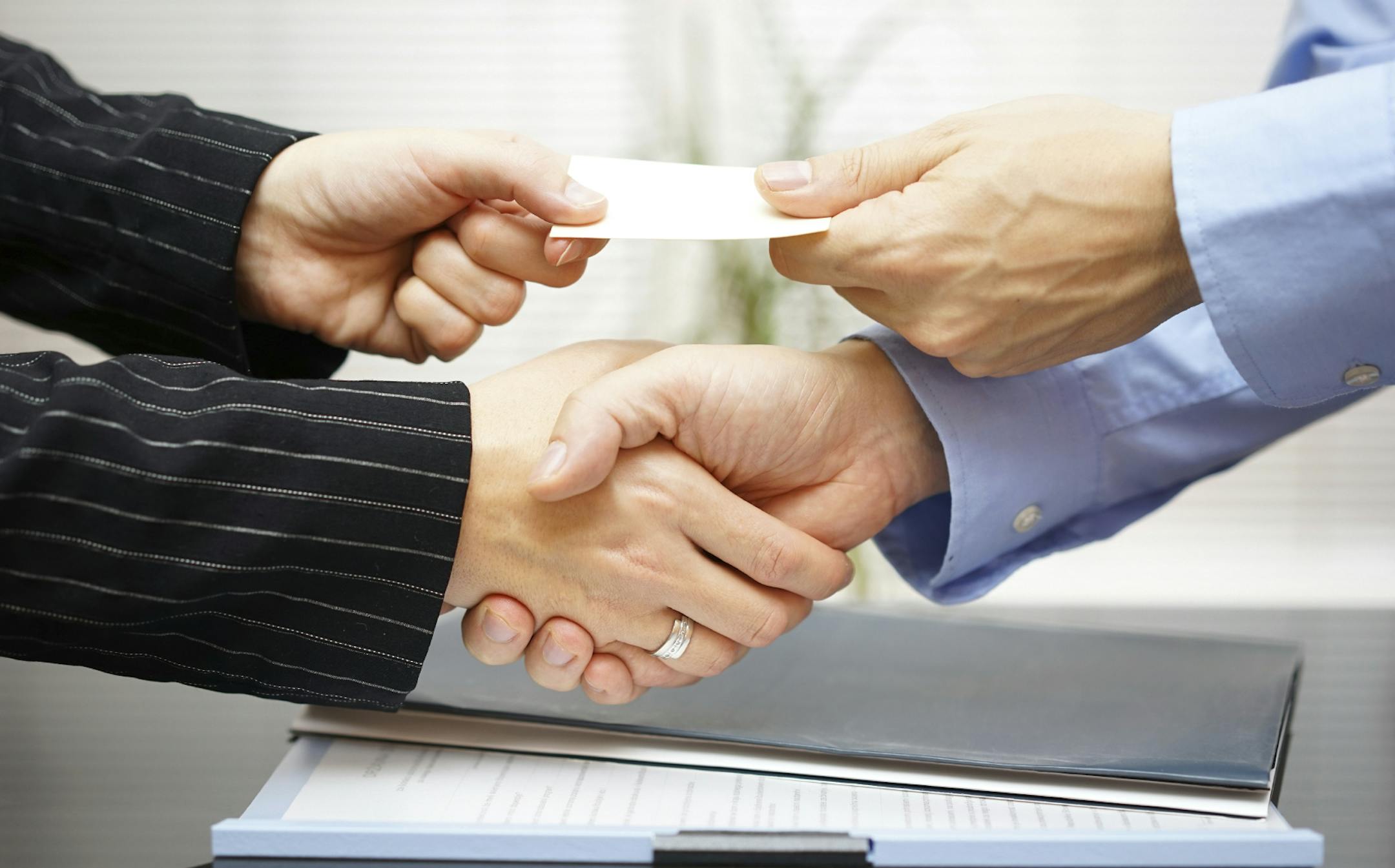 Business clients are exchanging business card and handshakeing after successful meeting