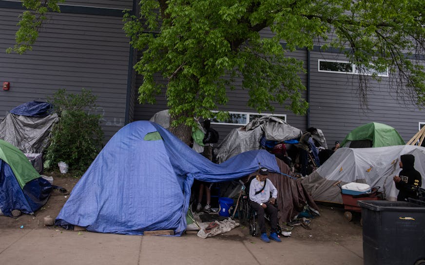 A man sits outside of a homeless tent camp in Minneapolis.