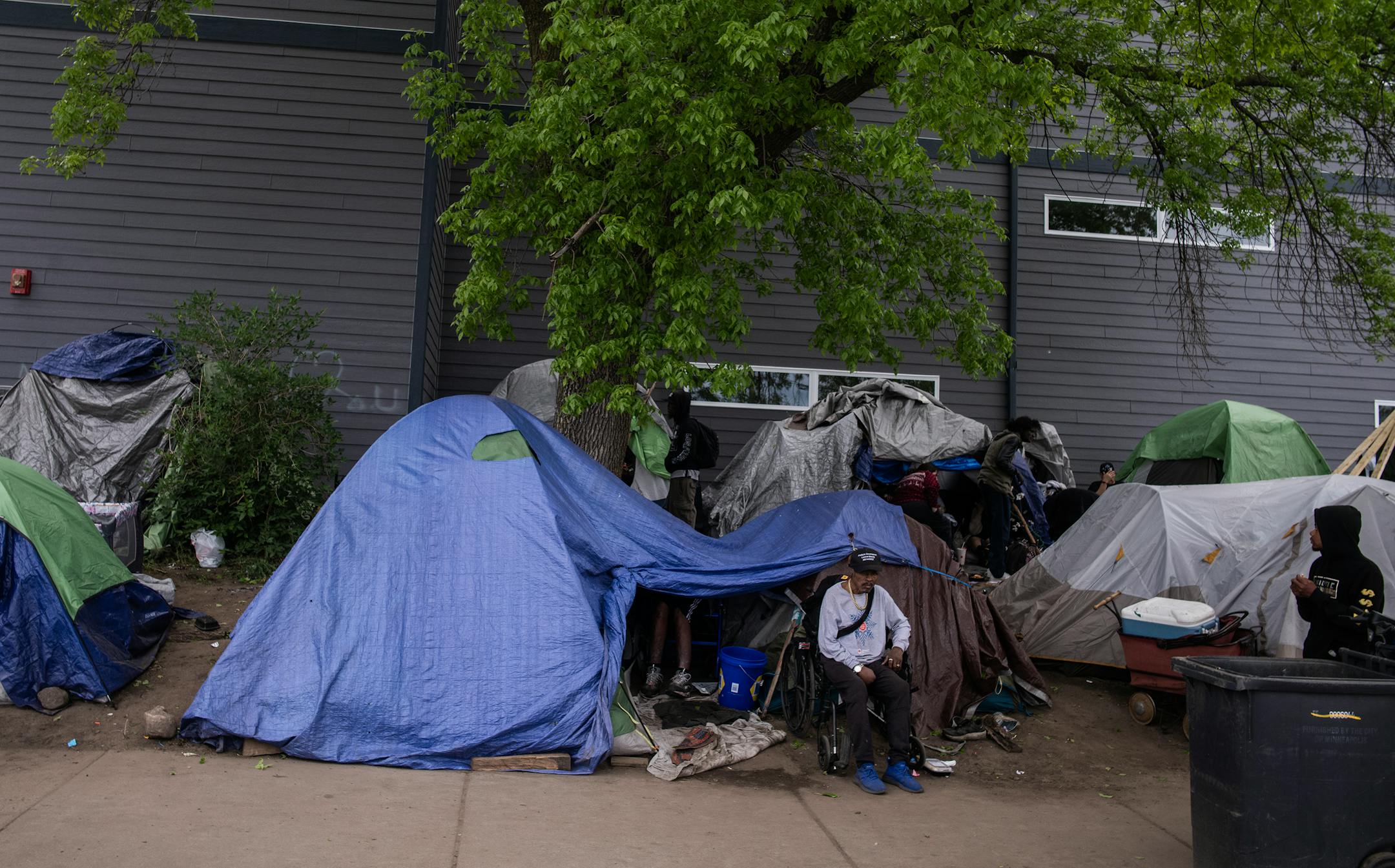 A man sits outside of a homeless tent camp in Minneapolis.