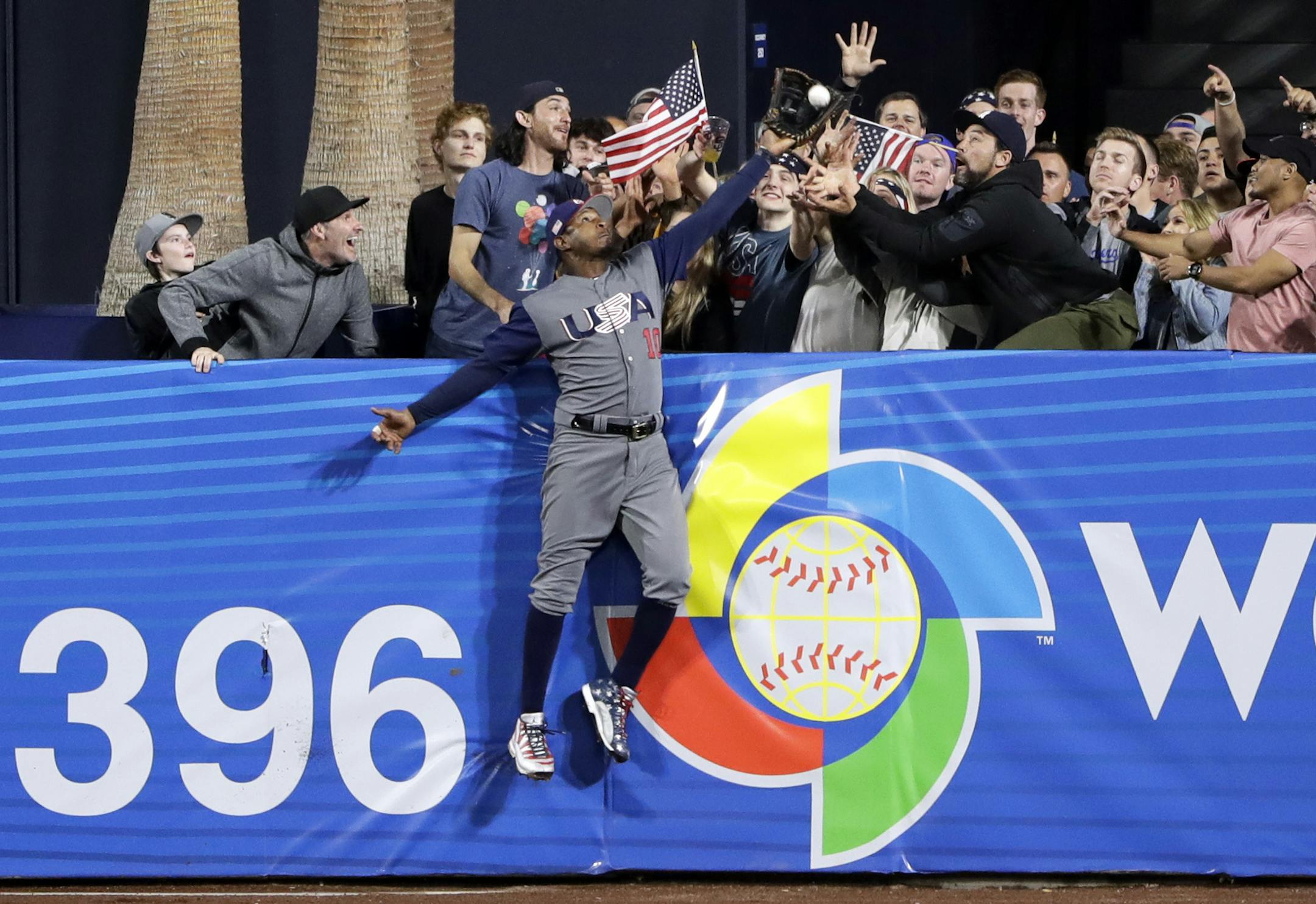 U.S. outfielder Adam Jones grabs a catch above the wall for the out on the Dominican Republic's Manny Machado during the seventh inning of a second-round World Baseball Classic baseball game Saturday, March 18, 2017, in San Diego. (AP Photo/Gregory Bull)