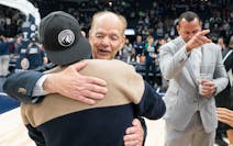 Timberwolves majority owner Glen Taylor hugs minority share owner Marc Lore while Alex Rodriguez looks on in January of 2023.