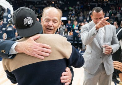 Timberwolves majority owner Glen Taylor hugs minority share owner Marc Lore while Alex Rodriguez looks on in January of 2023.