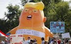 Demonstrators gather in front of an inflatable "Baby Trump" to protest the arrival of President Donald Trump outside Miami Valley Hospital after a mas