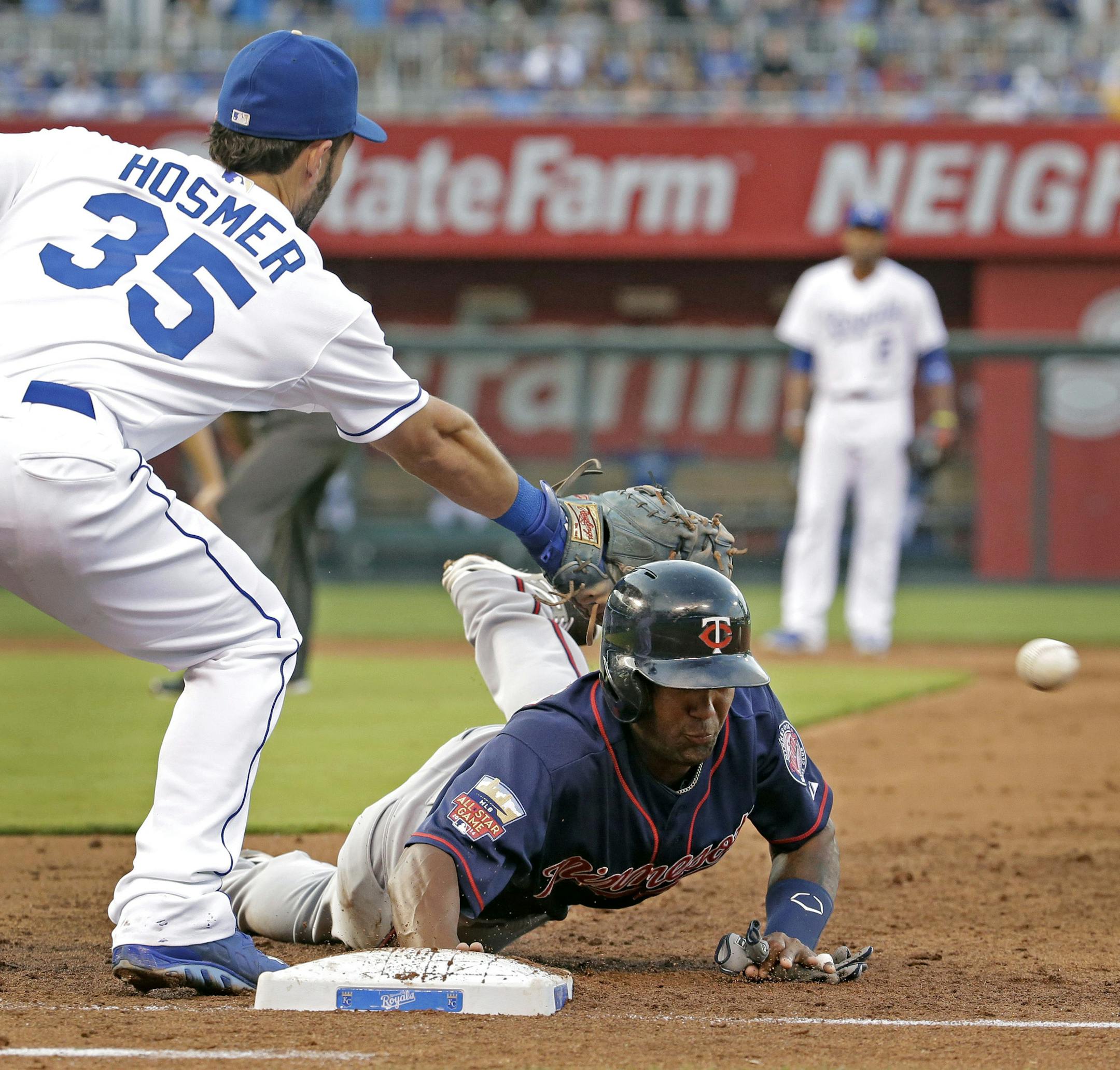 Minnesota Twins' Danny Santana dives back to first as Kansas City Royals first baseman Eric Hosmer tries to catch a wide throw by starting pitcher James Shields on a pick off attempt during the third inning of a baseball game Tuesday, July 29, 2014, in Kansas City, Mo. Santana advanced to second on the throwing error by Shields. (AP Photo/Charlie Riedel)
