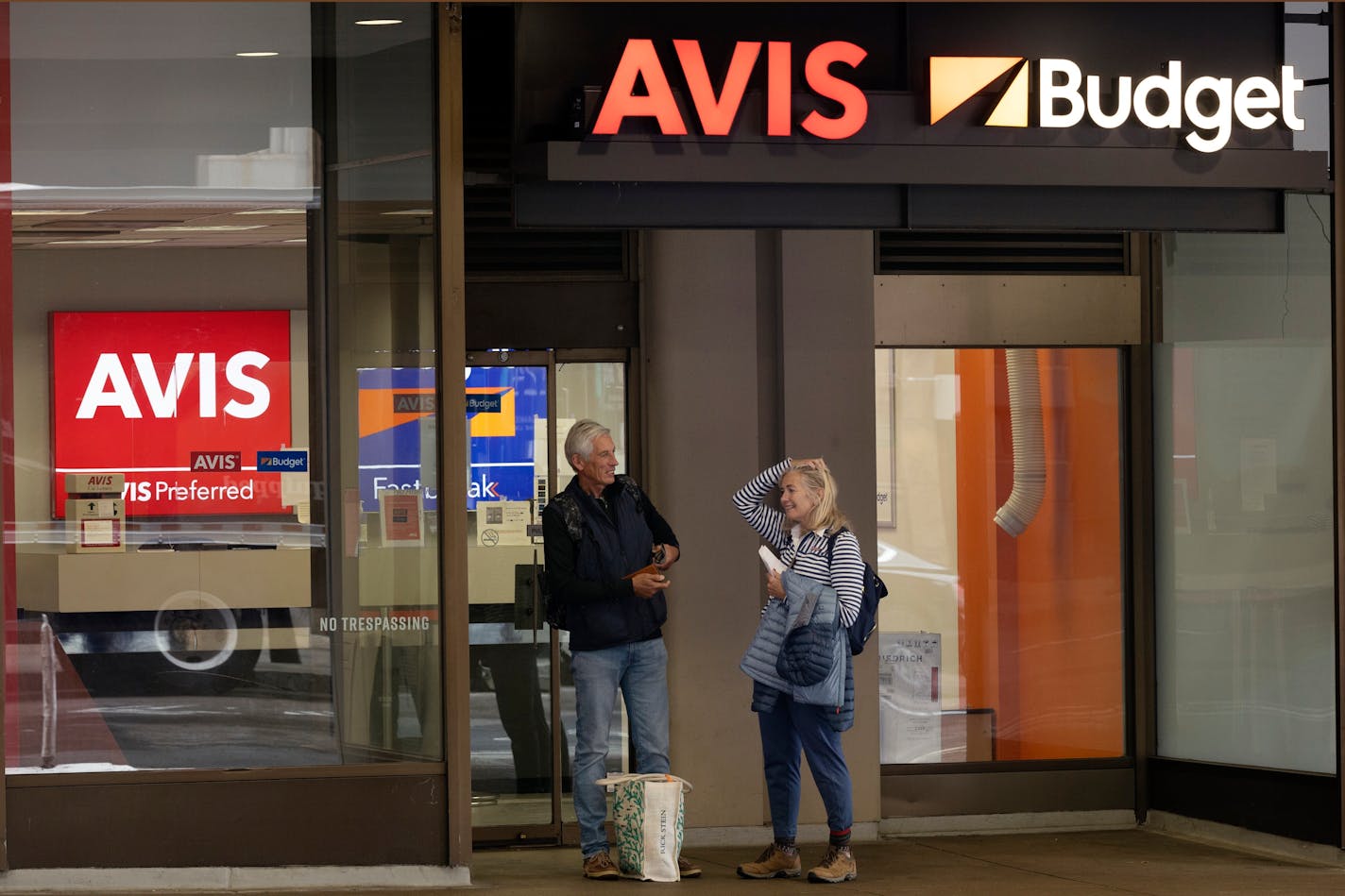 A couple stands in front of an Avis Budget rental car office, Friday, Oct. 14, 2022, in Boston. (AP Photo/Michael Dwyer)